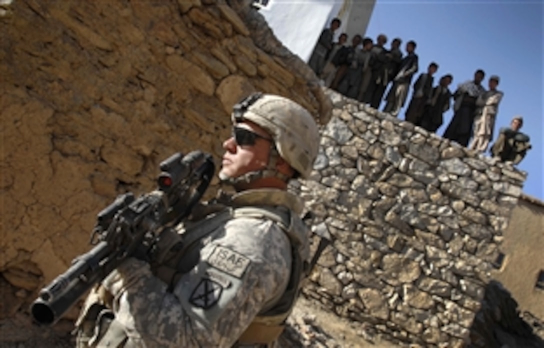 U.S. Army Spc. David Helton stands guard during a platoon leaders' meeting with tribal elders as local children look on in the village of Jalrez Valley in Wardak province, Afghanistan, March 12, 2009. U.S. military leaders met with local officials to assess their needs and discuss their concerns over the placement of a combat outpost nearby.