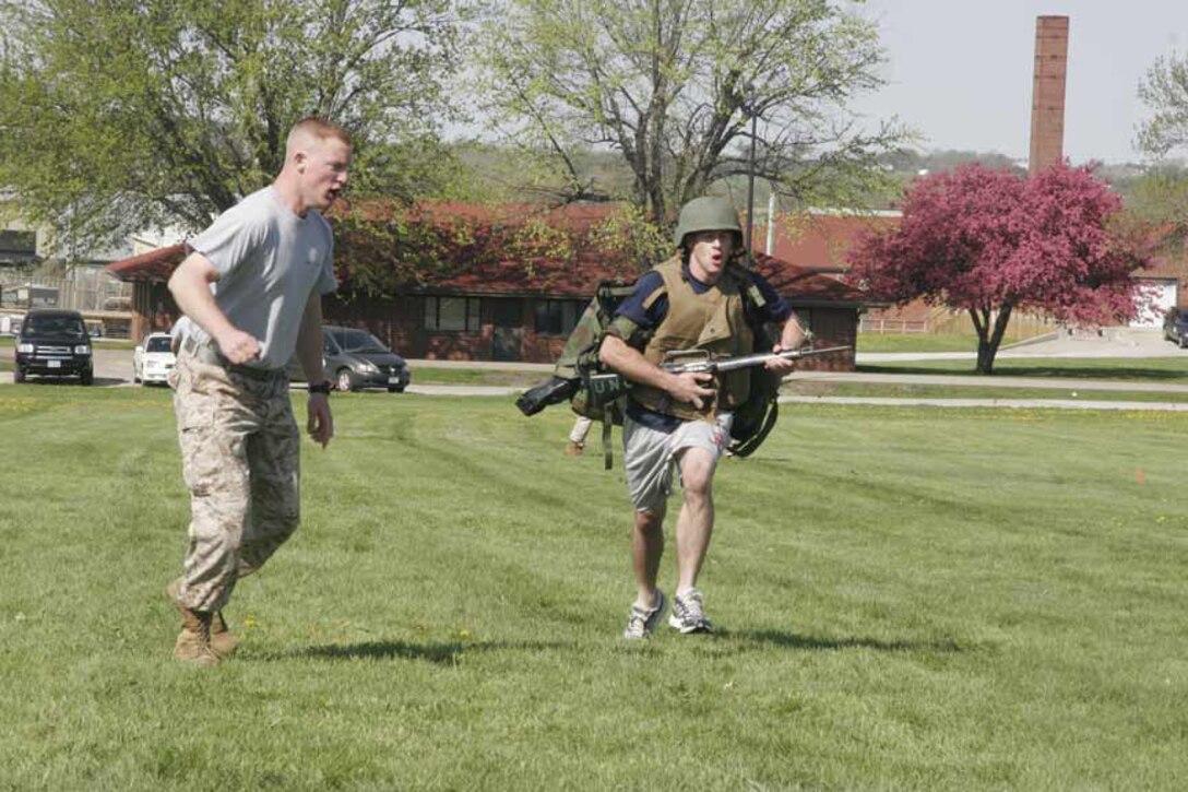 Sgt. Christopher Sorrell motivates a poolee May 2 during the combat gear run portion of Recruiting Station Des Moines' annual field meet. More than 400 poolees from across all of RS Des Moines' 12 recruiting substations competed in a wheel barrel race, tug-o-war, combat gear run, dizzy izzy and a modified combat fitness test. The field meet was designed to bring all of the RS's more than 400 poolees together for camaraderie and team building in a fun, competitive environment. Sorrell is a recruiter in Kearney, Nebraska. (U.S. Marine Corps photo by Sgt. Bryan A. Peterson)