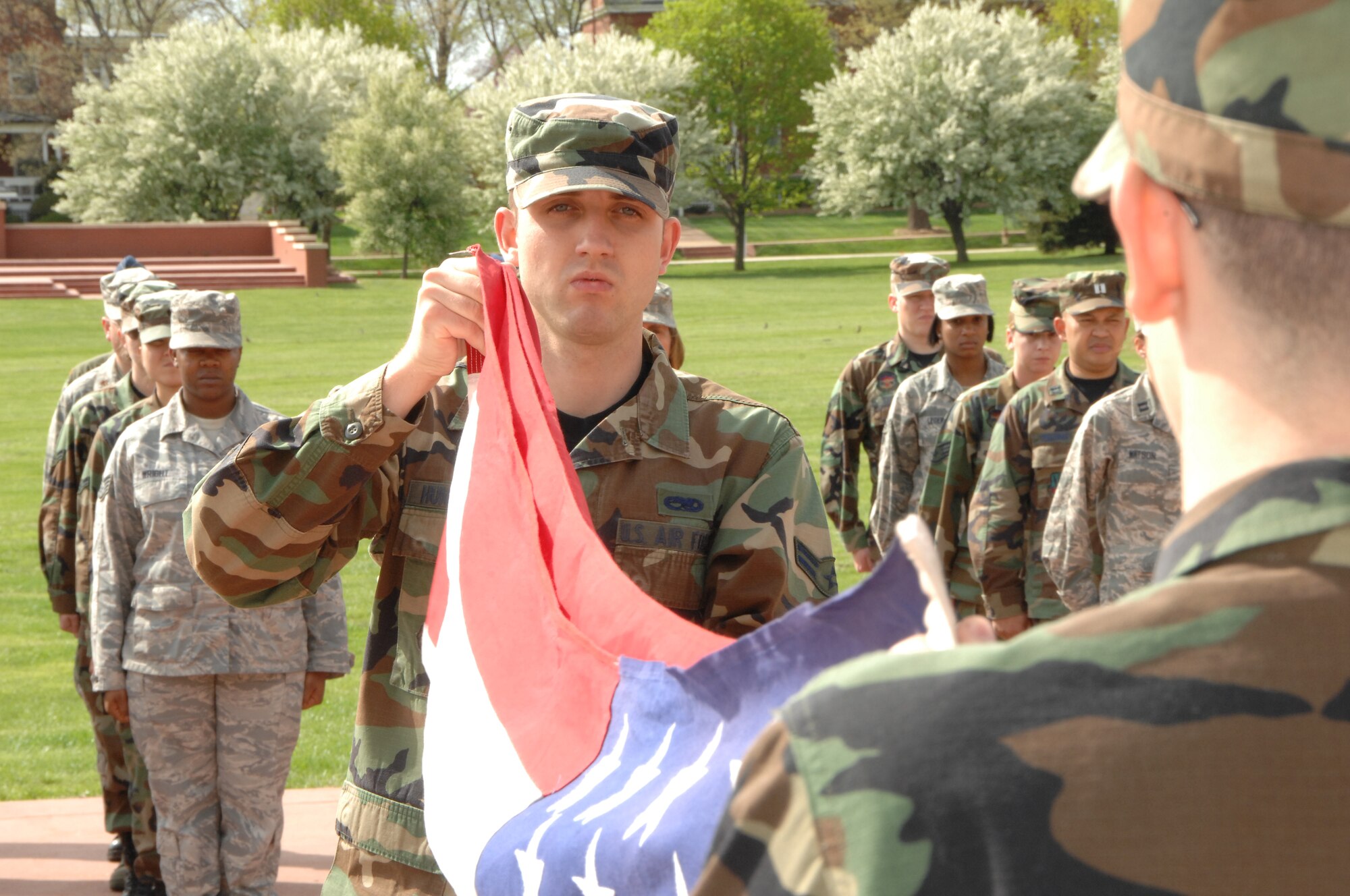 OFFUTT AIR FORCE BASE, Neb. - Members of the fighting 55th pay respect to the flag as members of the Offutt honor guard fold it, during a Retreat ceremony at the parade grounds here April 30. Retreat is an official ceremony which signifies the end of the duty day. U.S. Air Force photo by Dana Heard.