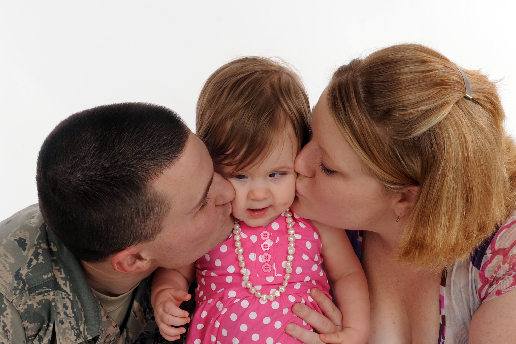 Senior Airman Derek Goodwin, 2d Maintenance Squadron, and his wife Stormy kiss their daughter Skyler. Skyler is blind with light perception due to Septo-optic Dysplasia. SOD can cause deficiencies in the pituitary, in addition to her blindness Skyler has to have injections and take pills for growth and hormone development. (U.S. Air Force photo by Senior Airman Joanna M. Kresge)