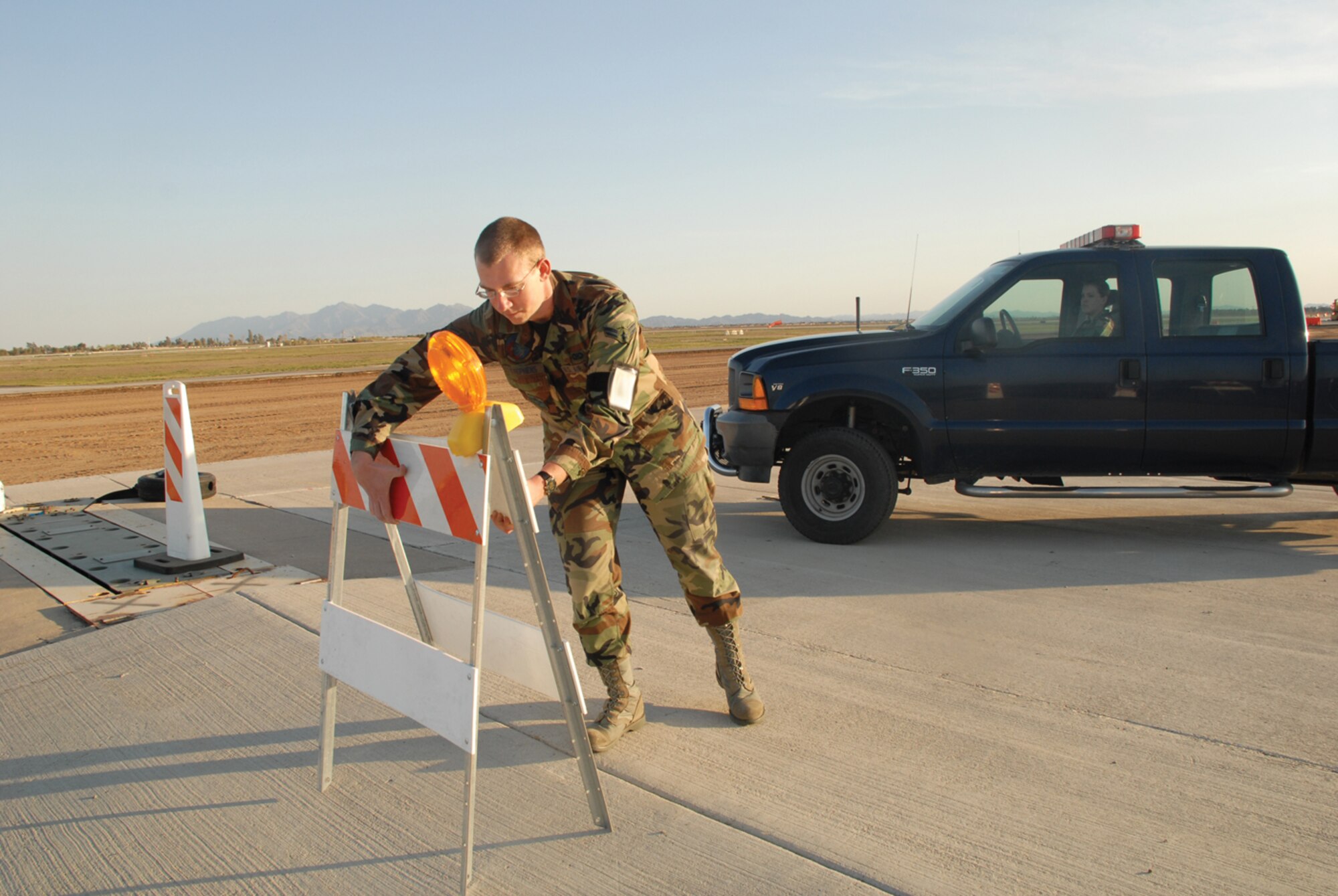Airman 1st Class Lawrence Stephens, 56th Operations Support Squadron airfield management operations coordinator, sets up barricades for a closed runway on the Luke Air Force Base flightline. (U.S. Air Force photo/ Airman 1st Class Tracie Forte.)