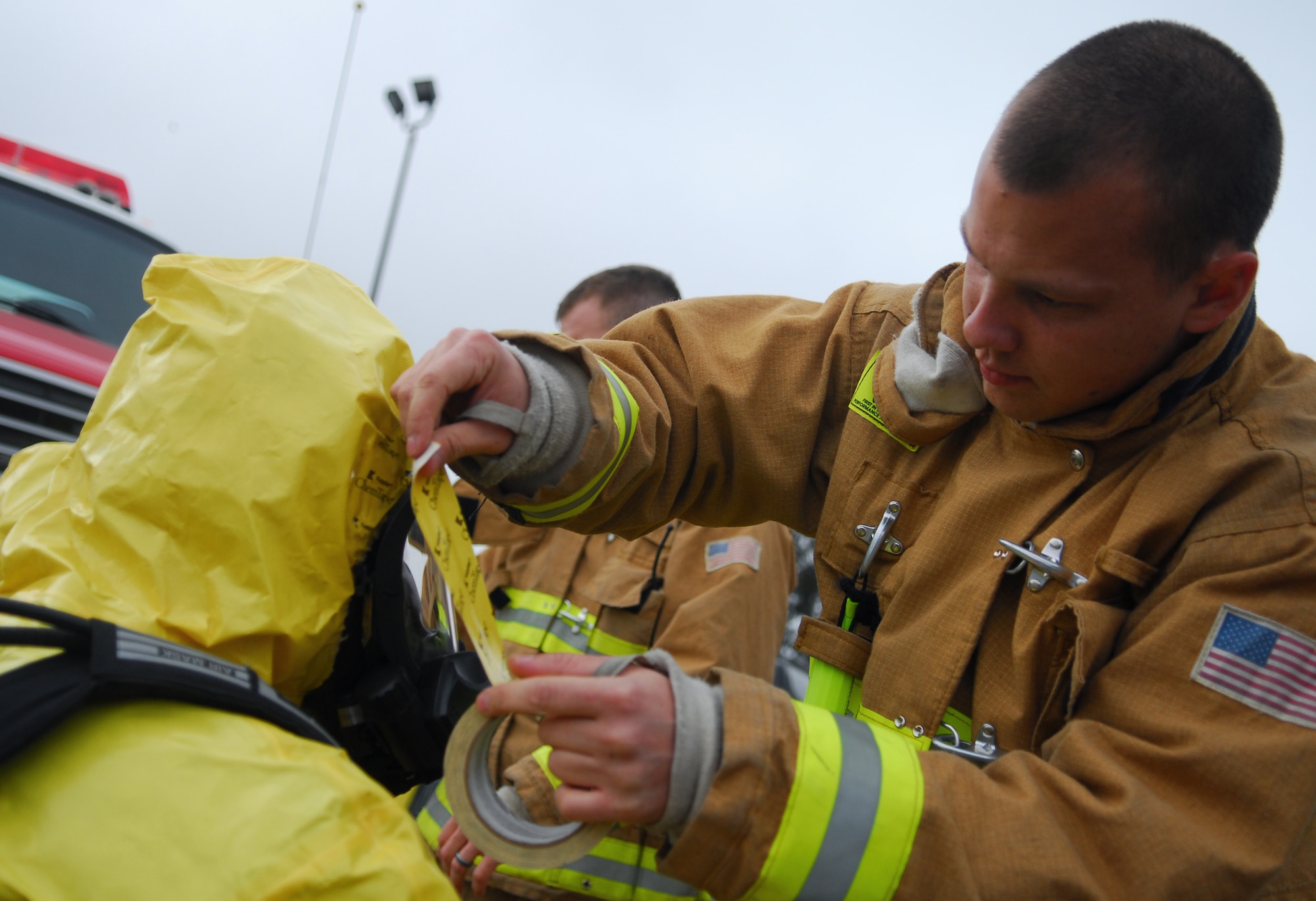 VANDENBERG AIR FORCE BASE, Calif.. -- Applying a strip of tape, a firefighter helps to ensure a chemical suit is properly donned during the Foggy Shores exercise here April 22. Excercises, like Foggy Shores, ensure base personnel are ready for any crisis situation. (U.S. Air Force photo / Senior Airman Christopher Hubenthal)