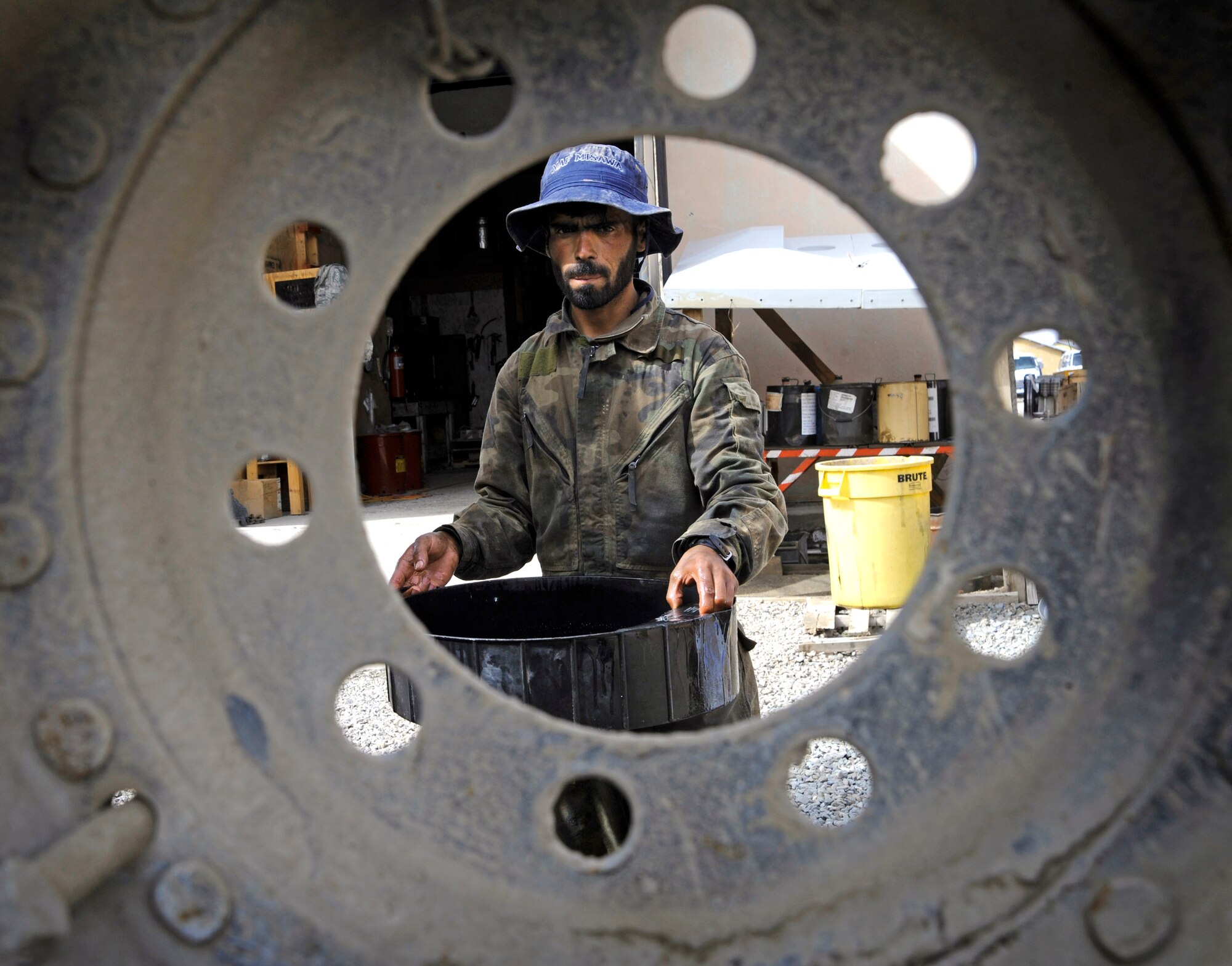 A local national working for the Paktya Provincial Reconstruction Team's vehicle maintenance unit carries a vat of oil he drained out of a medium tactical vehicle April 20 at Forward Operating Base Gardez, Afghanistan. (U.S. Air Force photo/Staff Sgt. Shawn Weismiller) 
