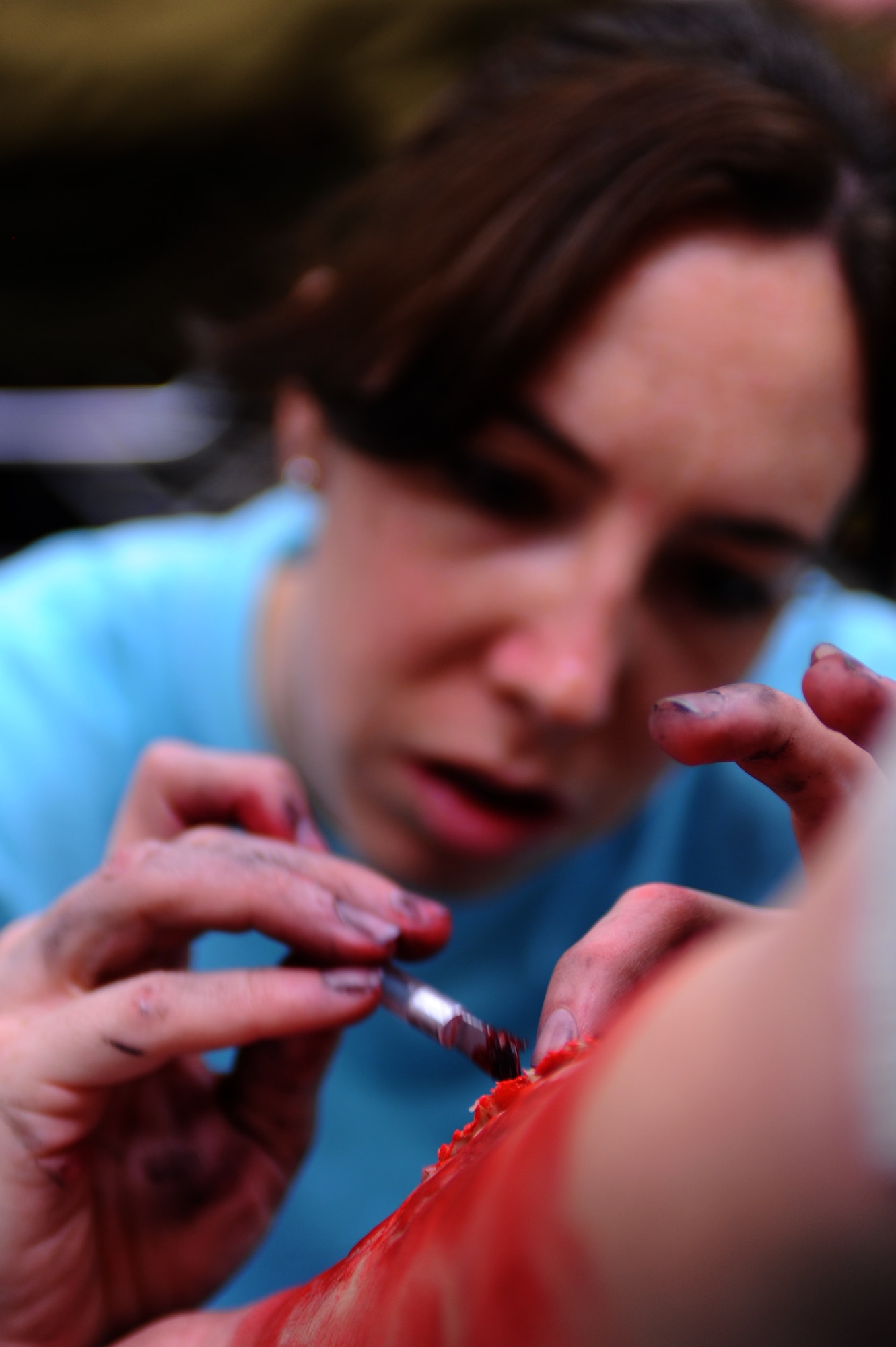 Senior Airman Ashley Barlow, 28th Medical Support Squadron patient administrator, creates a realistic wound on Angel Park’s arm, Western Dakota Technology College nurse student, as part of a major accident response exercise here, April 30. The exercise was tailored specifically to prepare for the Dakota Thunder air show. (U.S. Air Force photo/Senior Airman Kasey Zickmund)