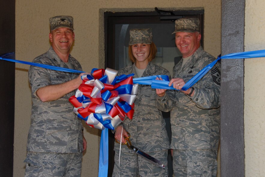 Airman Basic Lindsey Minnicker of Air University Education Logistics and Communications gets ready to cut the ribbon for the opening of the remodeled Stripes Lounge April 24. Looking on from left are 42nd Air Base Wing Commander Kris D. Beasley and Chief Master Sgt. Mark Repp, 42nd ABW command chief. The enlisted club at Maxwell, the Stripes Lounge has a new entrance on White Avenue with custom awnings, new flooring and furniture, a refinished bar area, different seating group areas, a fireplace, and updated paint scheme.  The lounge had been closed for about four months.