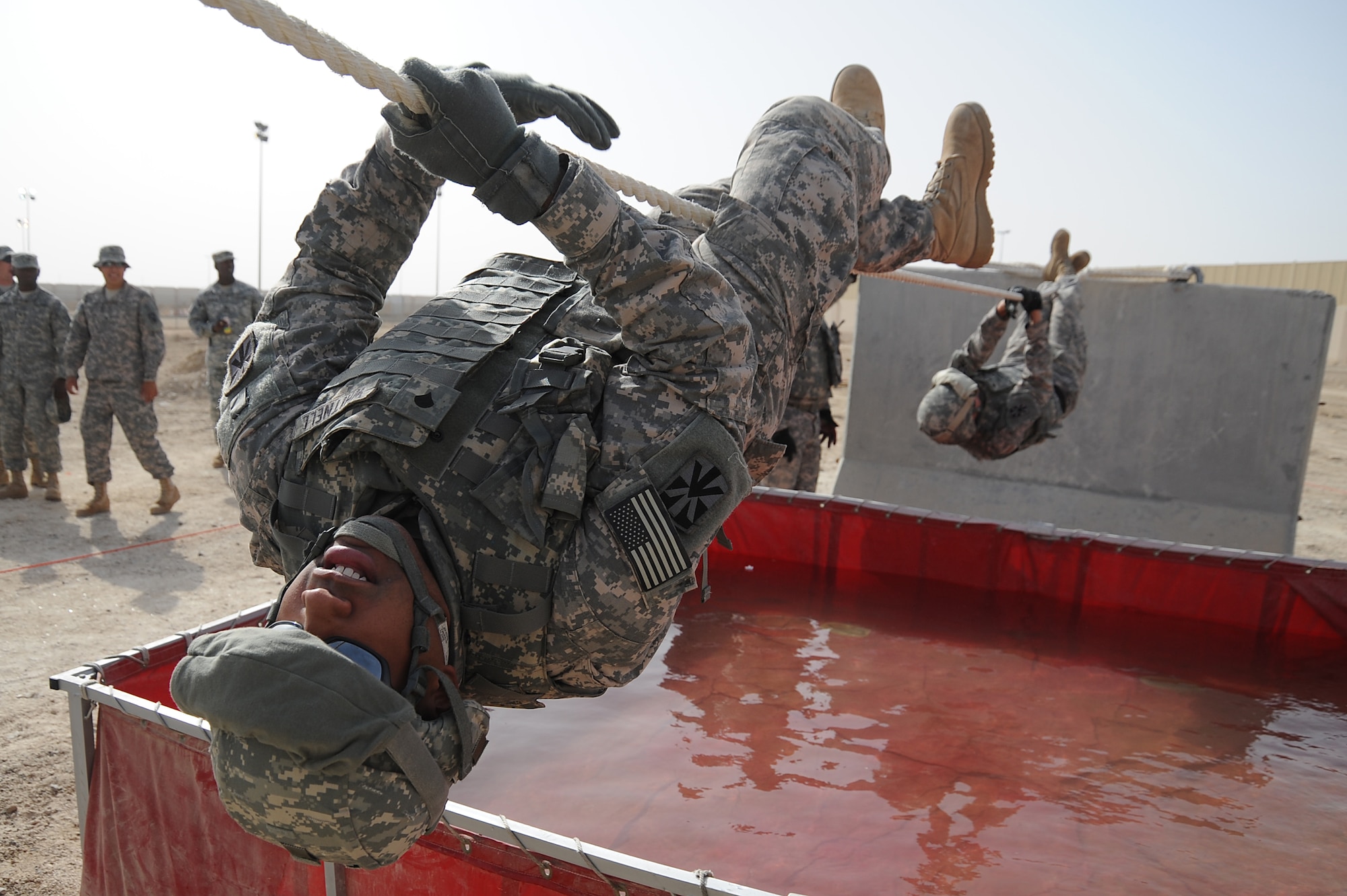 Spc. Alexandre Whitnell, 5-52 Air Defense Artillery Battalion, uses a 15ft rope to cross a water obstacle with his teammates following behind, during a Defender Challenge course, April 25 at an undisclosed location in Southwest Asia. The competition was close with his team finishing second place, just one second behind the winning team. Specialist Whitnell is deployed out of Fort Bliss, Texas and hails from Chicago, Ill.  (U.S. Air Force photo by Senior Airman Brian J. Ellis) (Released)