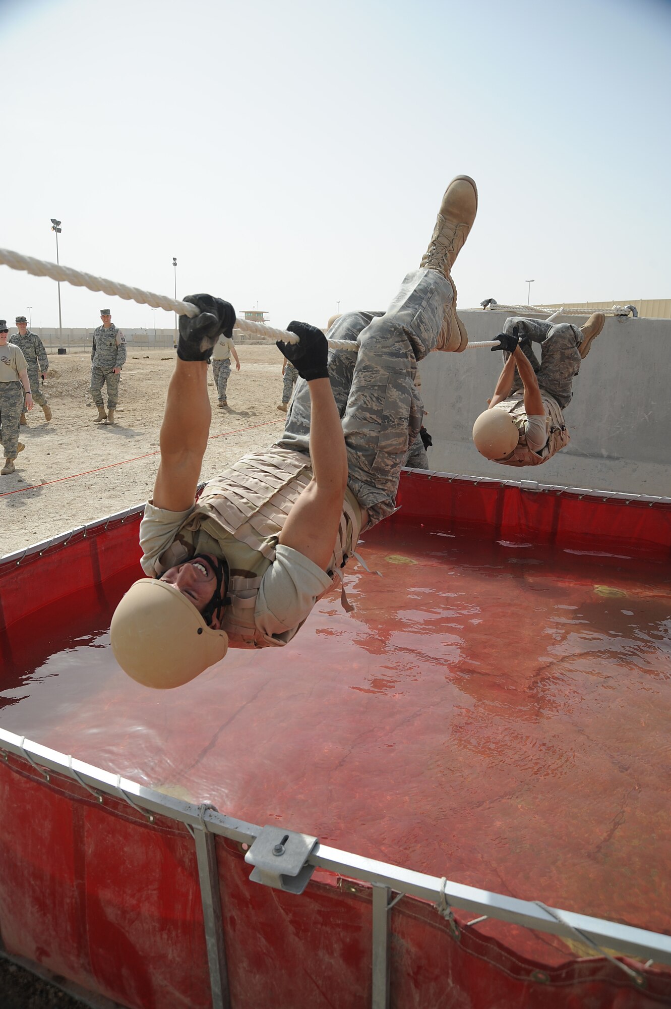 Senior Airman Matthew McCarthy, 380th Expeditionary Civil Engineer Squadron, uses a 15ft rope to cross a water obstacle with his teammates following, during a Defender Challenge course, April 25 at an undisclosed location in Southwest Asia. His team won the competition beating out second place by one second. Airman McCarthy is deployed from Bolling AFB, Wash. D.C. and hails from Omaha, Neb. (U.S. Air Force photo by Senior Airman Brian J. Ellis) (Released)