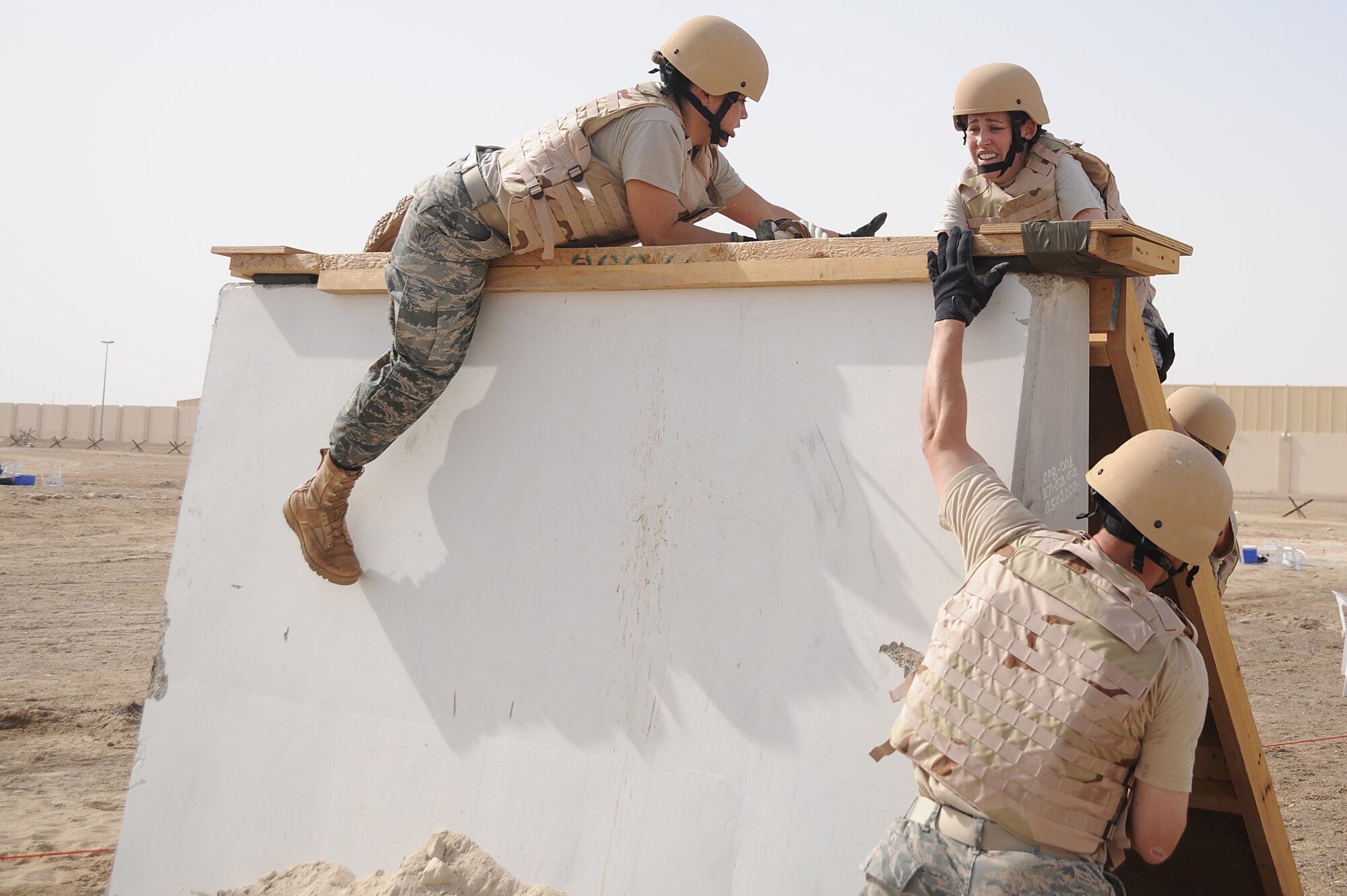 Staff Sgt. Christian Johnson, 380th Expeditionary Mission Support Group, lends a hand to 1st Lt. Miranda Thompson, 380th EMSG, as they use a rope to climb a wall on a Defender Challenge course, April 25 at an undisclosed location in Southwest Asia. Teams from different units ran the course, testing stamina, strength and brain power. Sergeant Johnson is deployed from Tyndall AFB, Fla. and hails from Brownsville, Texas. Lieutenant Thompson is deployed from Malmstrom AFB, Mont. and hails from Fleshing, Ohio. (U.S. Air Force photo by Senior Airman Brian J. Ellis) (Released)