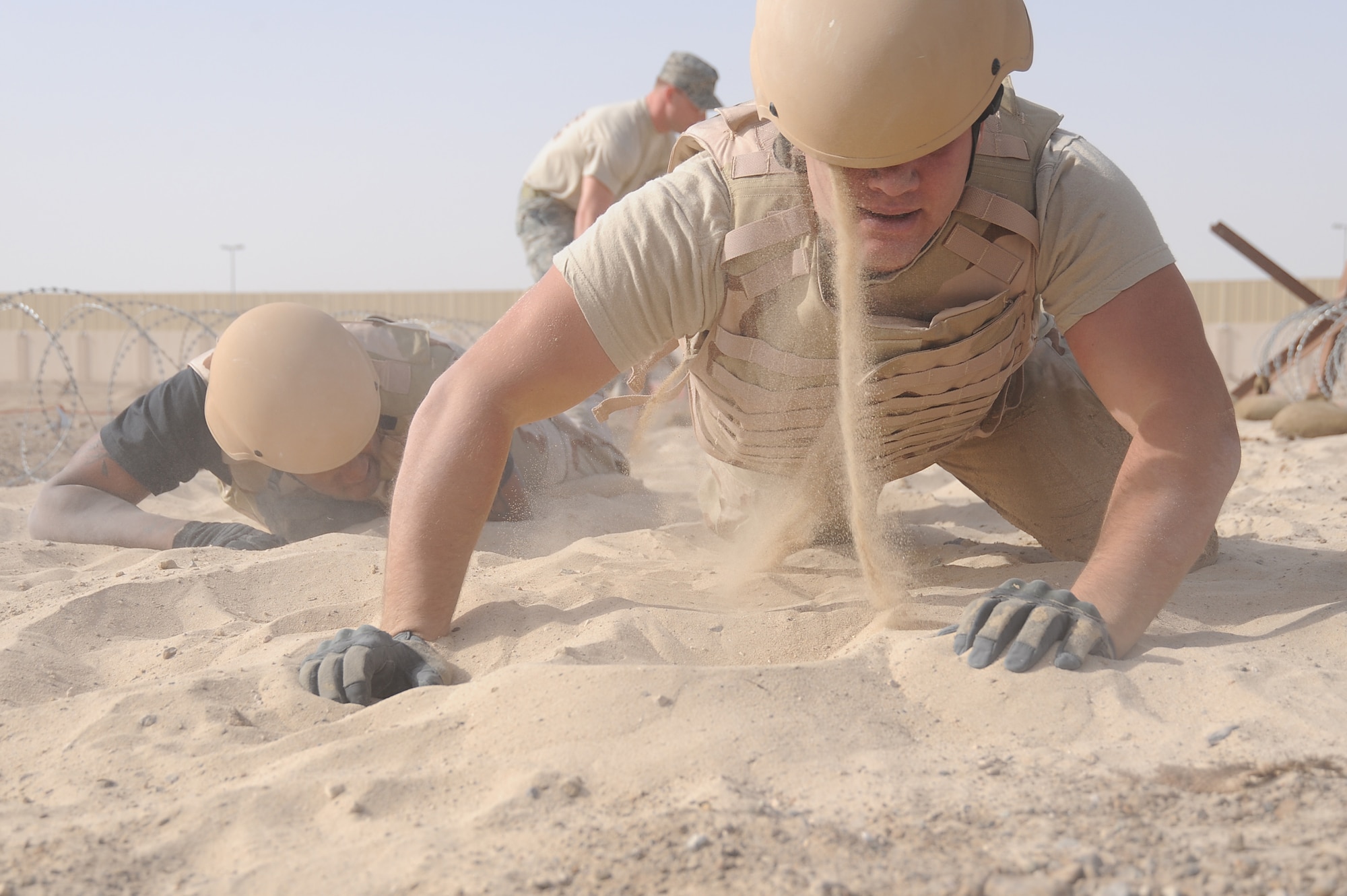 Sand falls from the helmet of Airman 1st Class Bryan Rozier, 380th Expeditionary Civil Engineer Squadron, as he gets up after low crawling 25ft through a sandpit on a Defender Challenge course, April 25 at an undisclosed location in Southwest Asia. Teams from different units ran the course, testing stamina, strength and brain power. Airman Rozier is deployed from Andrews AFB, Wash. D.C. and hails from Savannah, Ga. (U.S. Air Force photo by Senior Airman Brian J. Ellis) (Released)