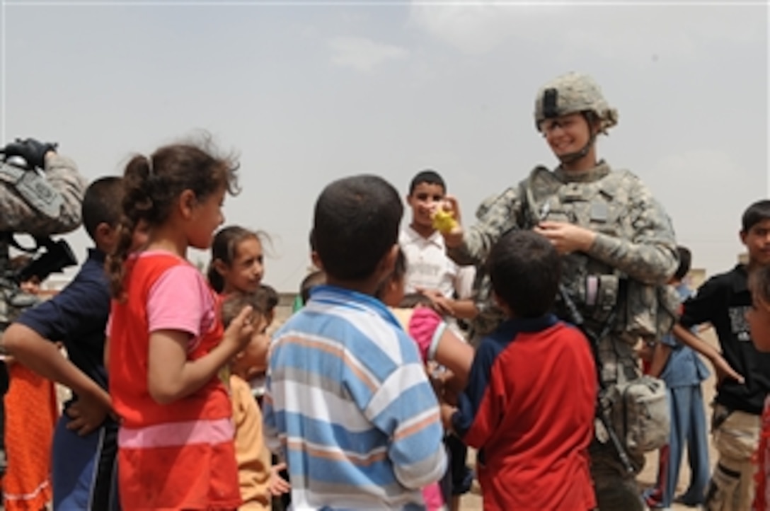 U.S. Army Spc. Nicole Willson a medic of Headquarters and Headquarters Company, 3rd Brigade Combat Team, 82nd Airborne Division hands out donated toys to local Iraqi children in the Al-Madain area of eastern Baghdad, Iraq, on April 18, 2009.  U.S. soldiers are in the area assessing soccer fields and distributing soccer balls donated in memory of a fallen U.S. soldier, Pfc. Nick Madaras.  