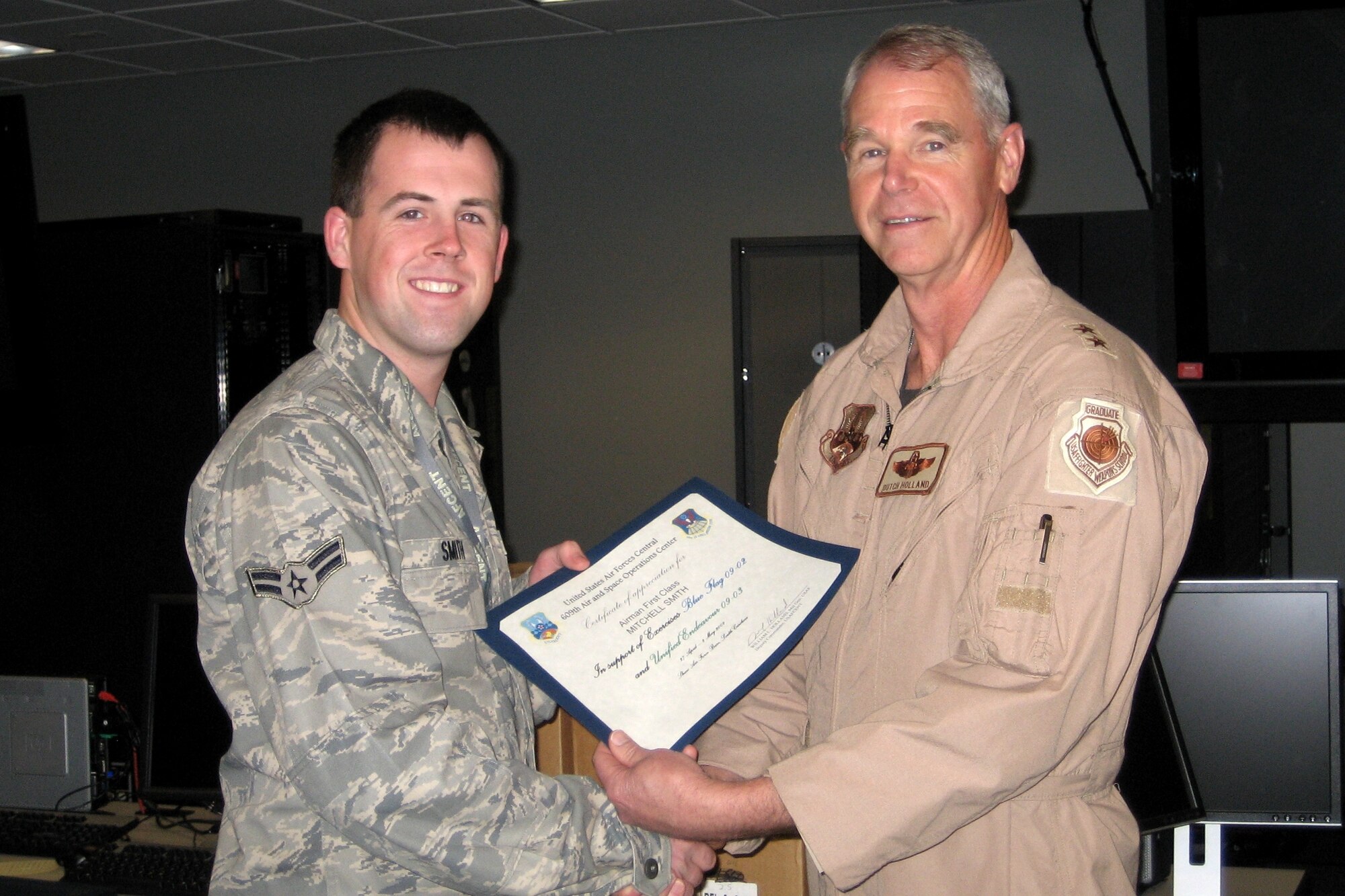 Airman 1st Class Mitchell Smith, combat reports technician, 103rd Air Operations Group, receives a certificate of appreciation from Major General William L. Holland, Deputy Commander, U.S. Air Forces Central, Shaw Air Force Base, S.C. for his contributions to Exercise Blue Flag.  (U.S. Air Force File Photo) 
