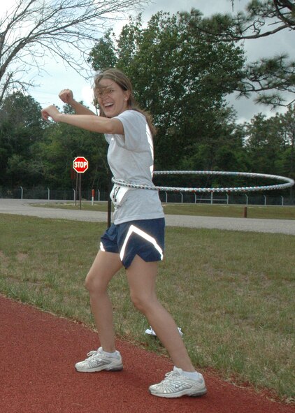 Tech. Sgt. Christina Pospichal, 919th Special Operations Wing, attempts the hula-hoop challenge at one of the stations set up along the track during her run. 919th members and their families participated in the base fun run at Duke Field, May 2.  Participants completed their trips around the track stopping at stations to attempt other challenges like jumping rope and doing push-ups. (U.S. Air Force photo/Staff Sgt. Jon McCallum)  