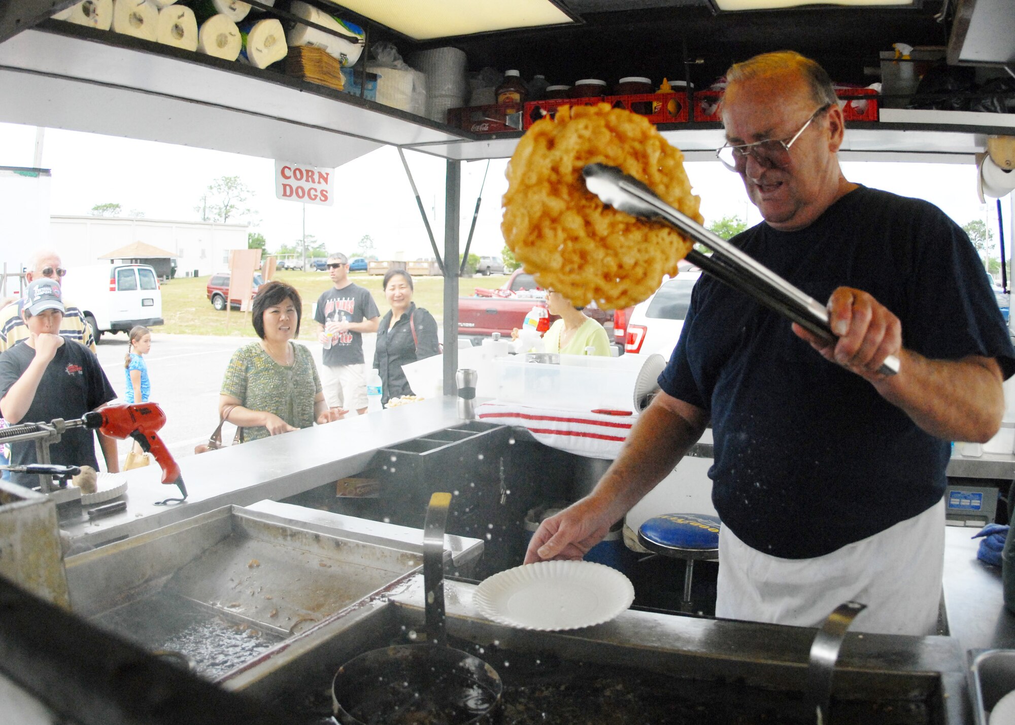 Ted Roberts, a 28-year Air Force veteran, dries a newly created funnel cake before adding a topping at his refreshment stand during the case lot sale held at Duke Field May 2. The retired lieutenant colonel sold refreshments and snacks to customers waiting to go into the warehouse.  The Fort Walton Beach native said that after he retired, his wife told him ‘he wasn’t going to play golf all day – he had to get a job.’  He has been running the refreshment stand ever since.  U.S. Air Force photo/Staff Sgt. Samuel King Jr.