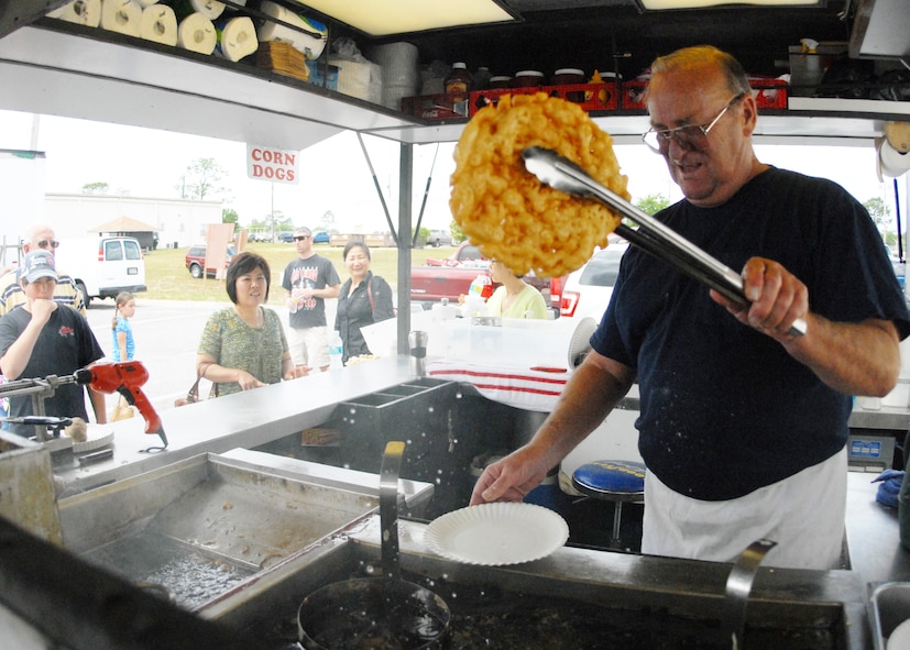 Ted Roberts, a 28-year Air Force veteran, dries a newly created funnel cake before adding a topping at his refreshment stand during the case lot sale held at Duke Field May 2. The retired lieutenant colonel sold refreshments and snacks to customers waiting to go into the warehouse.  The Fort Walton Beach native said that after he retired, his wife told him ‘he wasn’t going to play golf all day – he had to get a job.’  He has been running the refreshment stand ever since.  U.S. Air Force photo/Staff Sgt. Samuel King Jr.