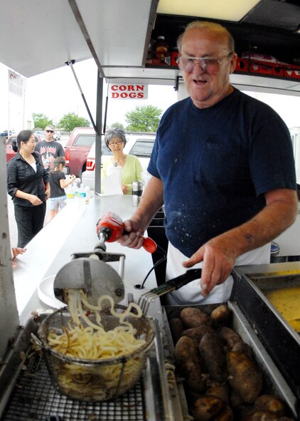 Ted Roberts, a 28-year Air Force veteran, uses his make-shift curly fry maker to fill up a basket before dropping them in the fryer at Duke Field May 2.  Mr. Roberts sold refreshments and snacks to the patrons of the case lot sale taking place May 2 and 3.  The retired lieutenant colonel added a drill to the handle of the fry maker to speed up the cutting process.  The Fort Walton Beach native said that after he retired, his wife told him ‘he wasn’t going to play golf all day – he had to get a job.’  He has been running the refreshment stand ever since.  U.S. Air Force photo/Staff Sgt. Samuel King Jr.