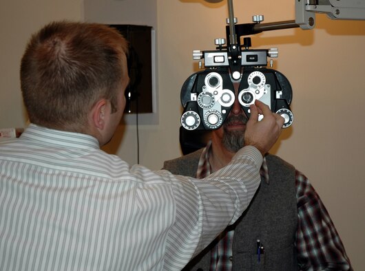 Marcus Simonich, an optometry intern from Pacific University, performs an eye examination on Joe Erickson April 25. Free eye exams and glaucoma screenings were available to retirees on a first-come, first-served basis during Retiree Appreciation Weekend April 24-25. The clinic treated 51 retirees, 10 received comprehensive exams.(U.S. Air Force photo/Valerie Mullett)