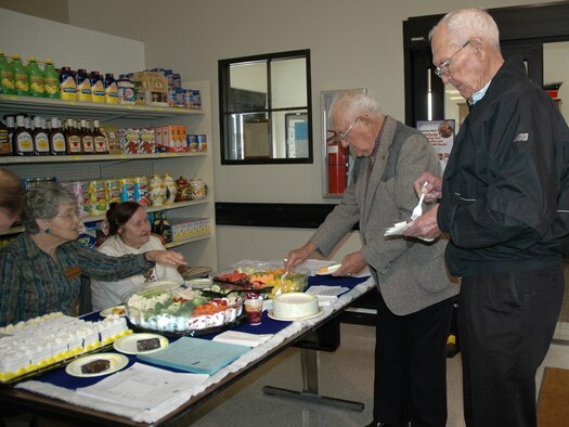 Retirees John Habeger (left) and Richard Brown enjoy some free fruit and cake provided by the Malmstrom Commissary. Montana Retiree Council members Vivian Peterson (left) and Marion Thul (right) greeted visitors as they entered the store April 25. (U.S. Air Force photo/Valerie Mullett) 
