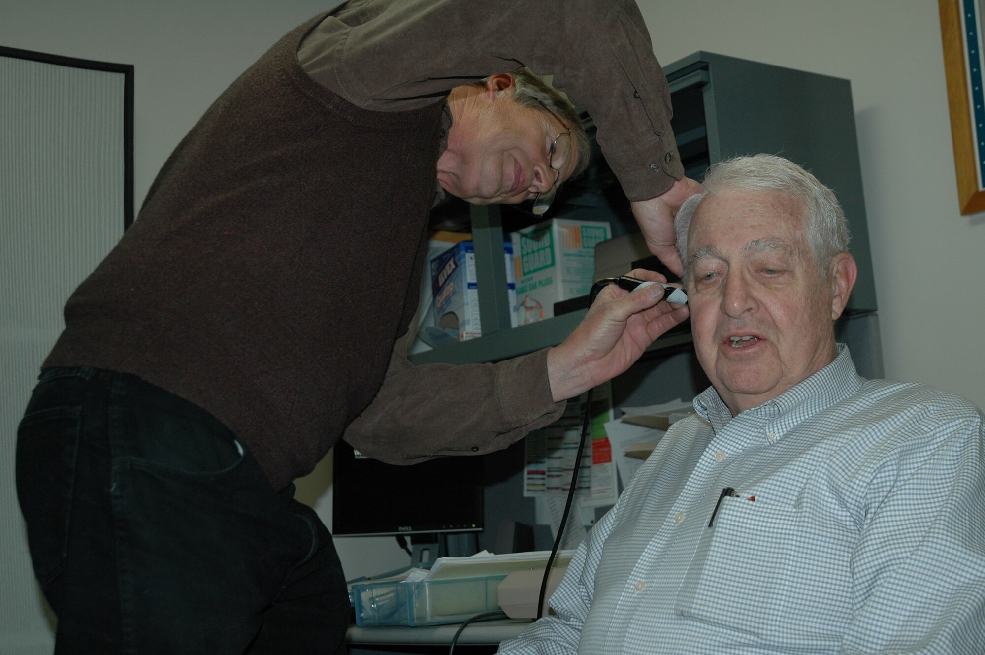 Jeff Griffin, an audiologist with Cascade Audiology, examines retired Lt. Col. Bill Wiseman's ear prior to performing a hearing test April 24 at the base clinic. These hearing exams were offered as part of Retiree Appreciation Weekend April 24-25. (U.S. Air Force photo/Valerie Mullett)