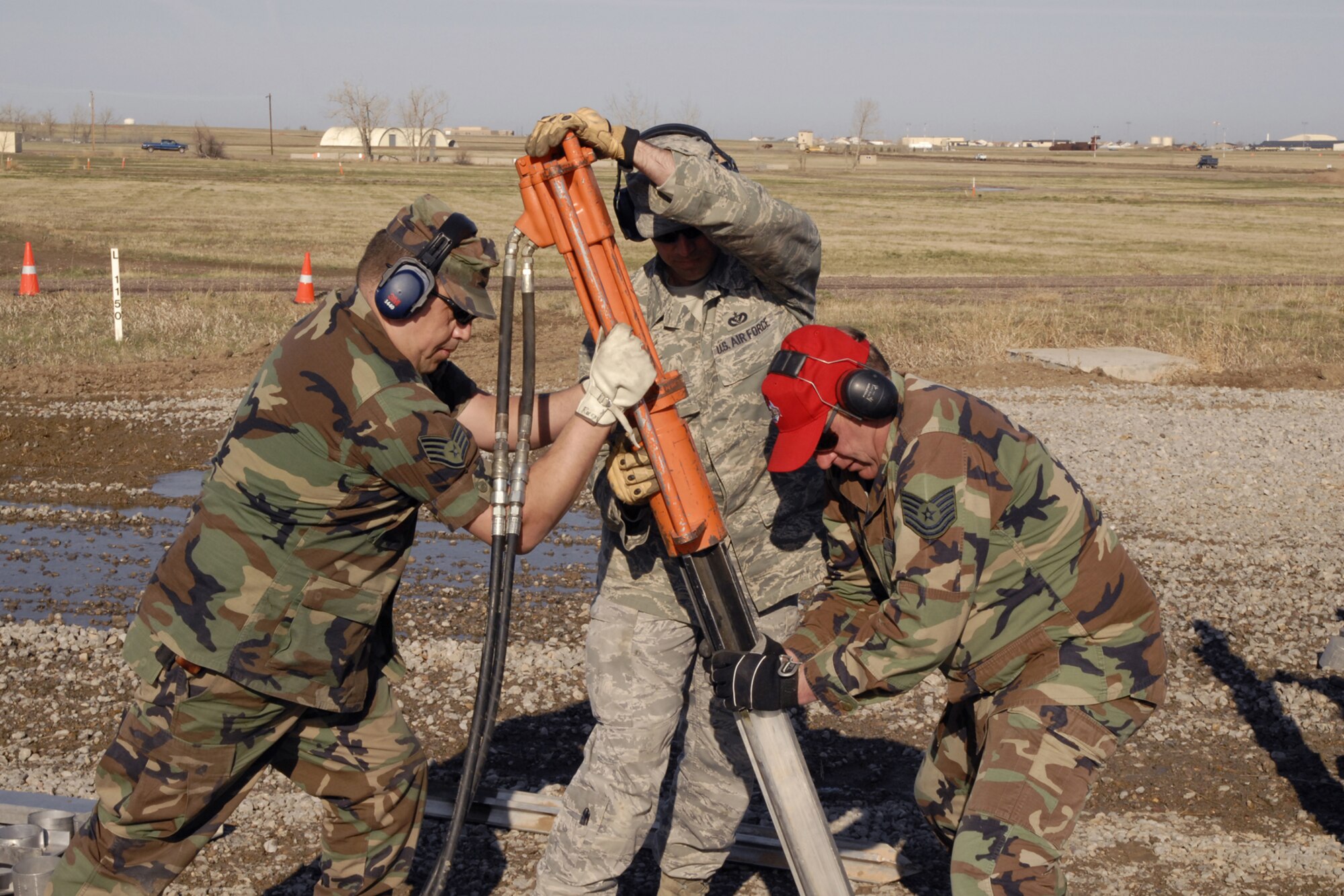 Members from three units join forces to drive one of 19 aluminum stake lines into the ground to secure a monile aircraft arresting system barrier during training April 17. From left are Staff Sgt. Steve Ramsay, 120th Fighter Wing; Tech. Sgt. Brett Bare, 341st Civil Engineer Squadron; and Tech. Sgt. Jeff Butler, 219th RED HORSE Squadron. All three military members work in the power production areas of their units. (U.S. Air Force photo/Beau Wade)
