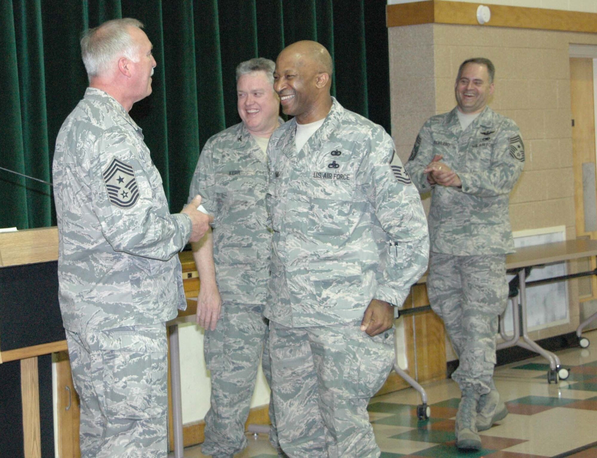 MCGUIRE AIR FORCE BASE, N.J. -- Reservist Master Sgt. Derek Williams, center, shares a laugh with 22nd Air Force Command Chief Master Sergeant James R. Fields Jr., while receiving a certificate of participation in the Senior NCO Leadership Development Course held April 24-25 here. The Air Force Reserve Command course provides SNCOs the chance to explore in-depth communications, trust, teamwork and leadership issues and initiatives. (U.S. Air Force photo/Staff Sgt. Monica L. Dalberg)