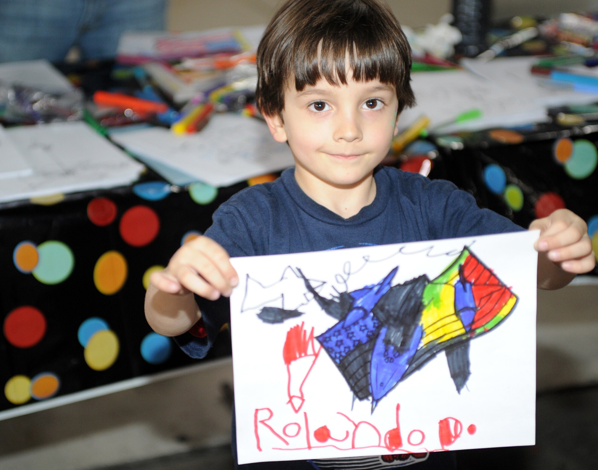 Rolando Carner, son of Major Brett Carner from the 3rd Medical Operations Squadron, holds up a drawing he colored at the Spring Break-up Party on April 24. Each year this party offers hours of family fun to all military members and their families. (U.S. Air Force photo by Senior Airman Laura Turner)