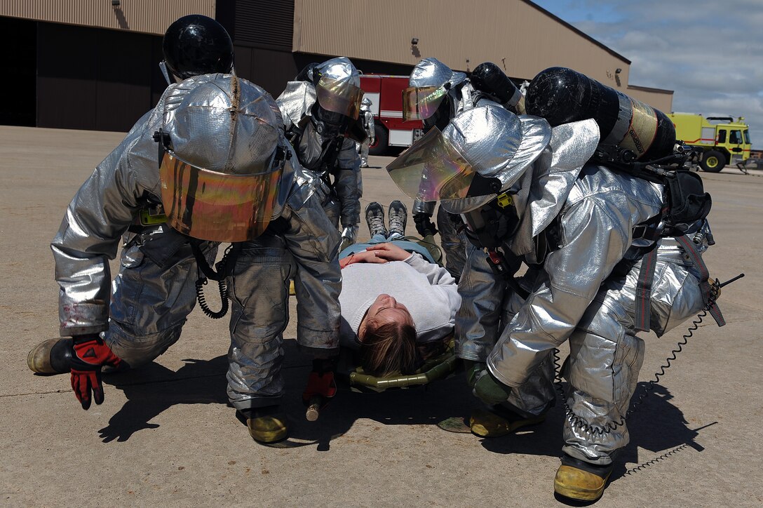 Members of the 28th Civil Engineer Squadron fire department use a carrier to lift a person with a simulated injury on a long spine board during a major accident response exercise here, April 30.  There were 22 people used as role players for the exercise, which was tailored specifically to prepare for the Dakota Thunder air show. (U.S. Air Force photo/Airman 1st Class Joshua J. Seybert)