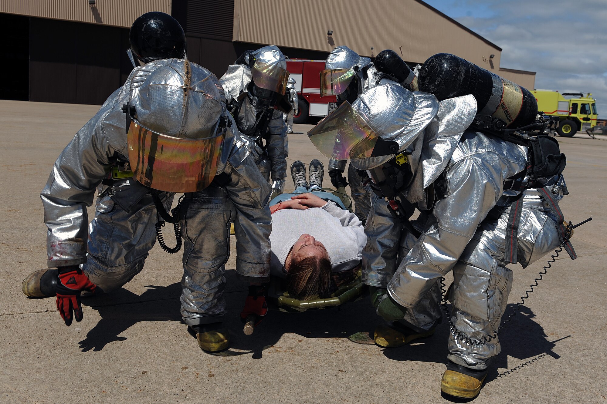 Members of the 28th Civil Engineer Squadron fire department use a carrier to lift a person with a simulated injury on a long spine board during a major accident response exercise here, April 30.  There were 22 people used as role players for the exercise, which was tailored specifically to prepare for the Dakota Thunder air show. (U.S. Air Force photo/Airman 1st Class Joshua J. Seybert)