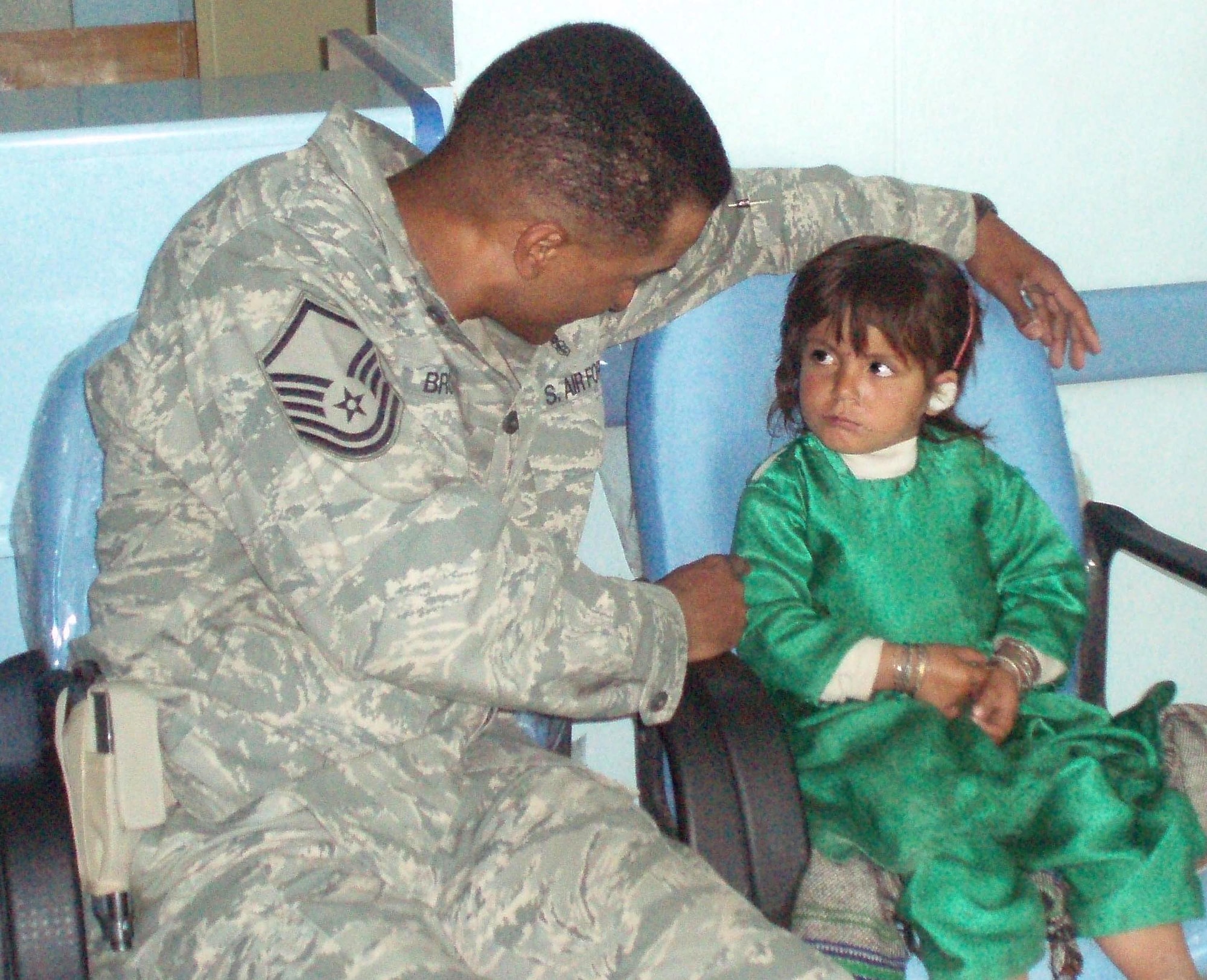 Master Sgt. Dewane Brown, Medical Embedded Training Team mentor deployed to Afghanistan from Ellsworth, comforts an Afghani girl suffering from an ear infection. Sergeant Brown is part of a team of specialists working to bring modern medical technology and capabilities to the Afghan people. (Courtesy photo)