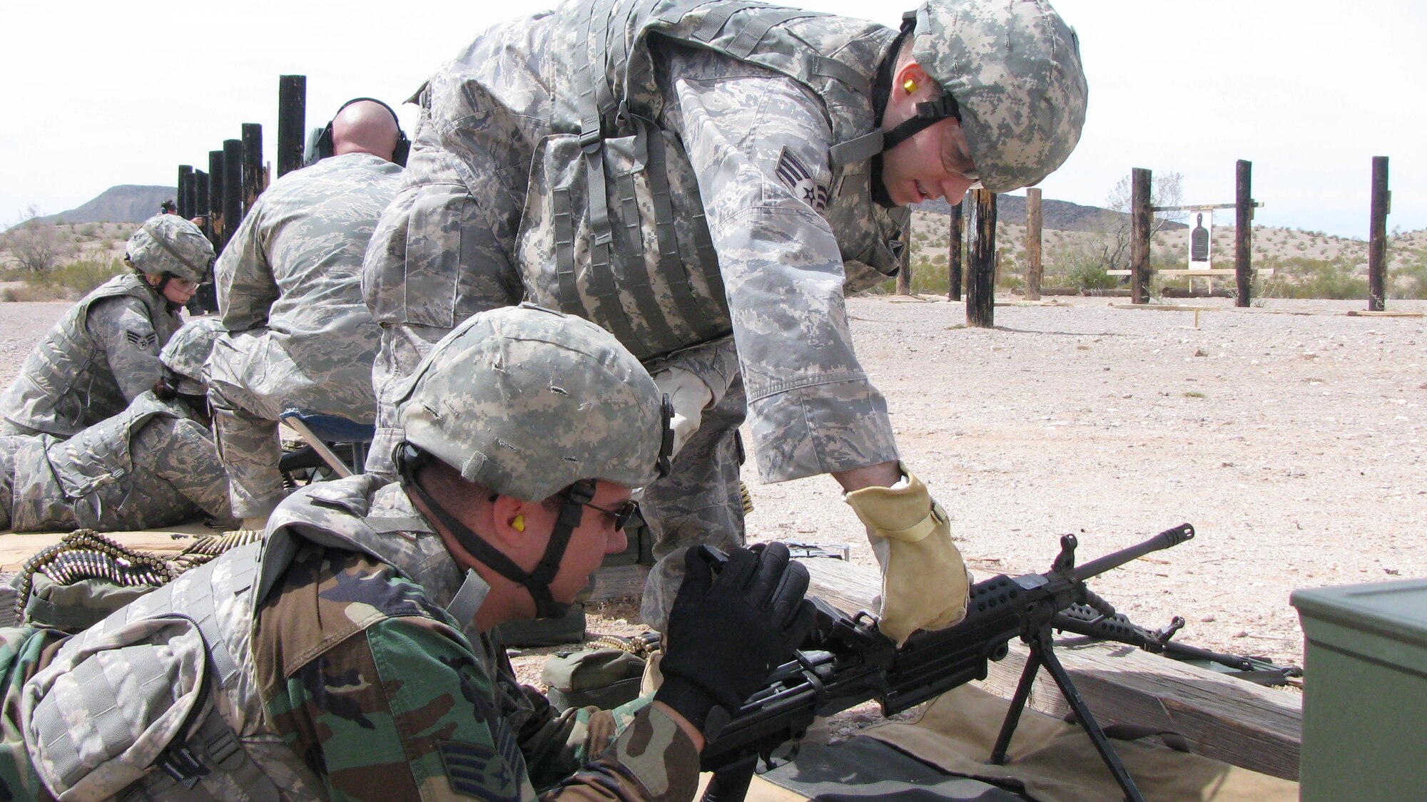 Senior Airman Chad Finch changes the barrel of the M-249 for Staff Sgt. Jarrett Sainz during annual weapons qualification May 2 at Gila Bend, Ariz. The barrel must be changed every 200 rounds to avoid overheating. Airman Finch and Sergeant Sainz are members of the 944th Security Forces Squadron. (U.S. Air Force photo/Staff Sgt. Daryl Gladstein)