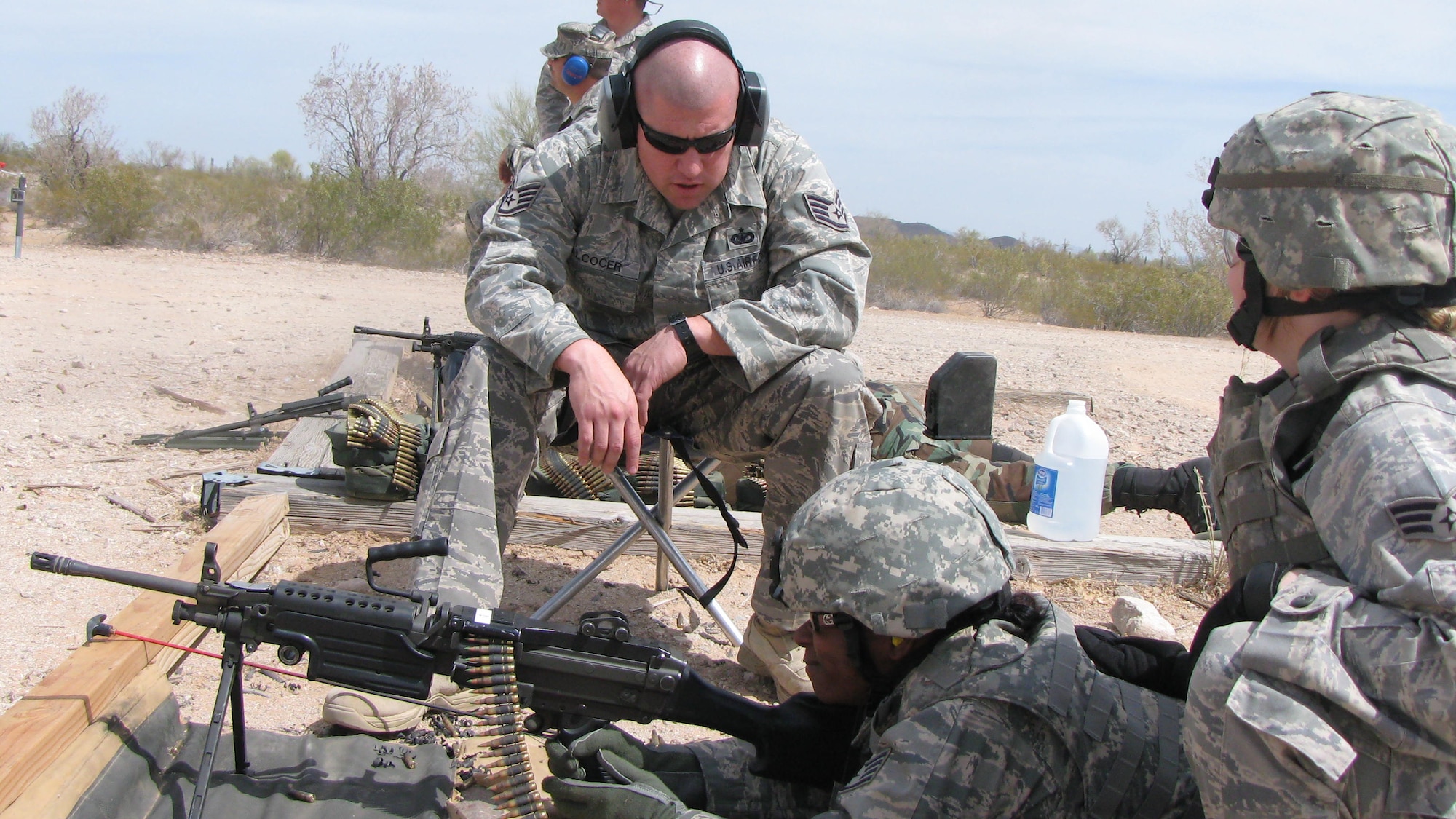 Staff Sgt. Francisco Alcocer provides instruction to Staff Sgt. Christie Willis on the M-249 while her assistant gunner, Senior Airman Sarah Schuster, aids in target aquisition during annual weapons qualification May 2 in Gila Bend, Ariz. All three are members of the 944th Security Forces Squadron. (U.S. Air Force photo/Staff Sgt. Daryl Gladstein)