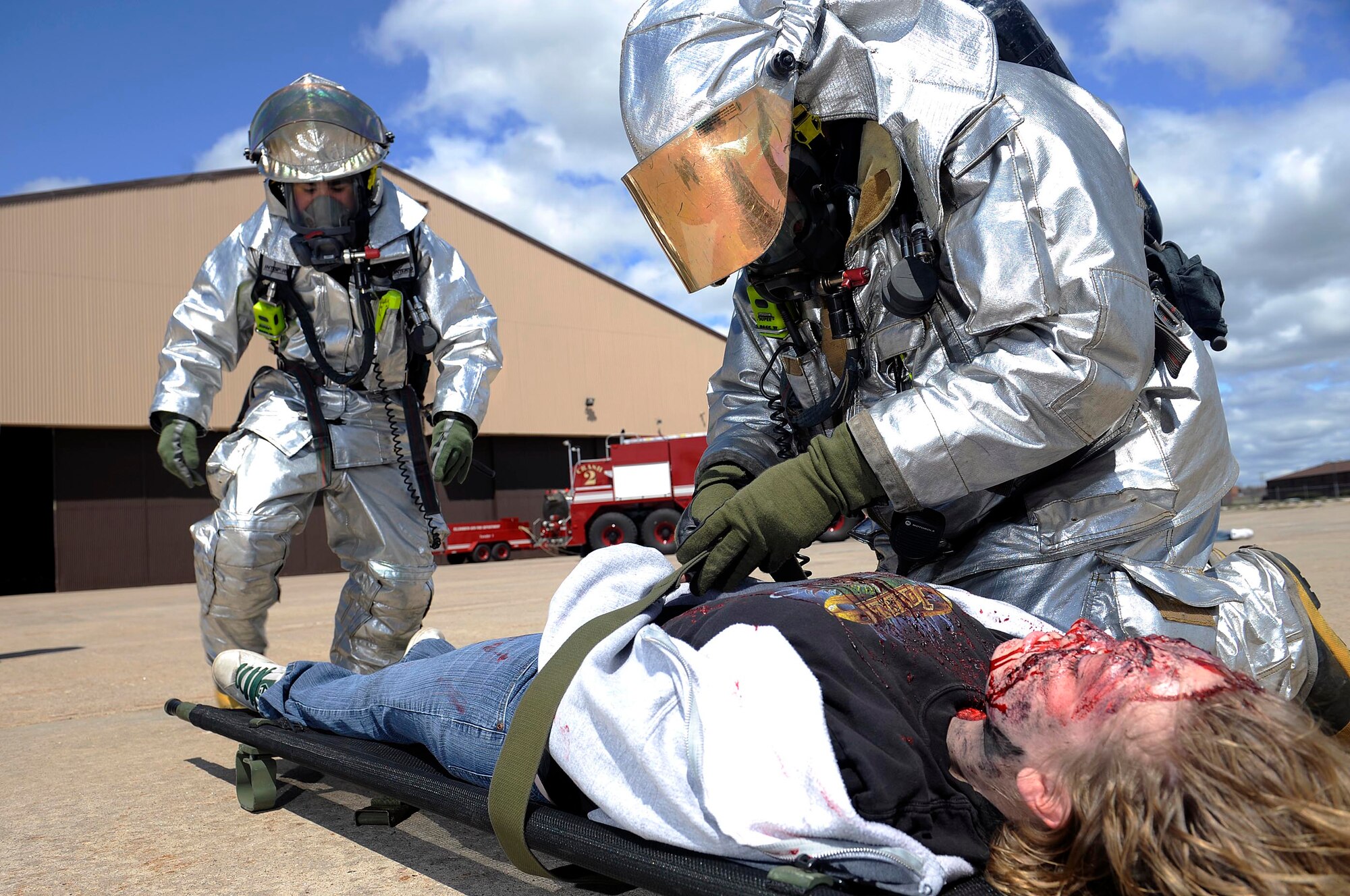 Staff. Sgt. Francis Bierman and Airman 1st Class Eric Ibarra, 28th Civil Engineer Squadron firefighters, strap role-player Emily Stevens, Western Dakota Technology College nurse student, onto a litter during a major accident response exercise here, April 30.The exercise was performed to test Ellsworth Airmen on their accident response capabilities in preparation for the upcoming air show. (U.S. Air Force photo by Airman 1st Class Corey Hook)