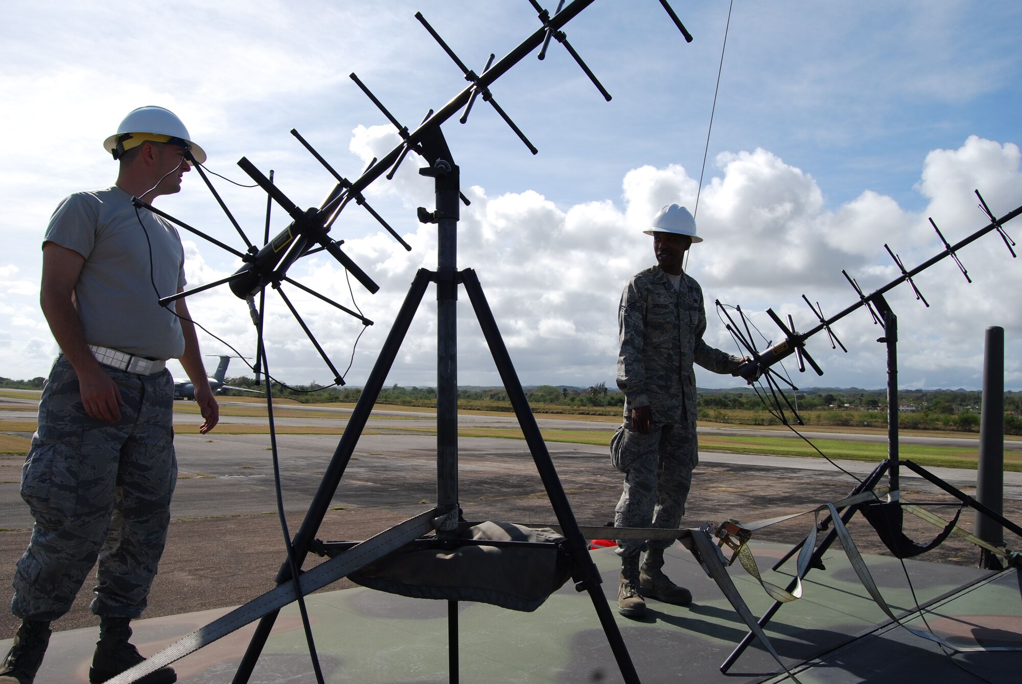 Off to an early start as the sun rose over the Rafael Hernandez International Airport during Patriot Hoover, Staff Sgt. Michael Lewis and SRA. Amos Gregory set up satellite communications on top of the Mobile Air Reporting Center (MARC ).  The antennas provide satellite phone and radio communications between aircraft and the 433rd Airlift Control Flight during Patriot Hoover as they approach the airport in Aguadilla, Puerto Rico. (U.S. Air Force Photo/Staff Sgt. Carlos Trevino)