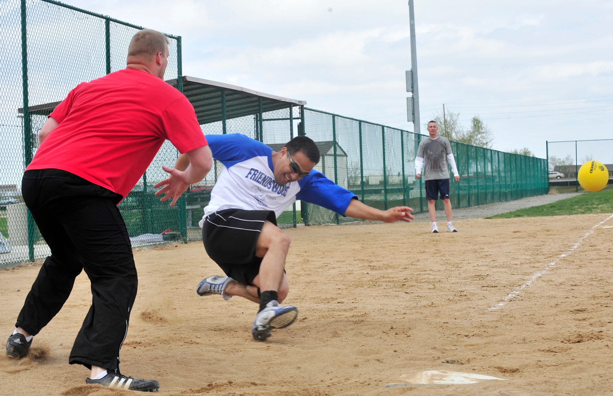 BUCKLEY AIR FORCE BASE, Colo. -- Danny Wong, 460th Medical Group, slides safely into home beating the throw during the Fitness Center's lunctime kickball tournament here April 30. Twelve teams participated in the tournament, where the 460th MDG won with a victory over the Marines in the championship game. The Fitness Center holds monthly lunchtime tournaments to promote physical fitness and esprit de coprs. For more information contact the Fitness Center at 720-847-6679. (U.S. Photo by Senior Airman Alex Gochnour)  