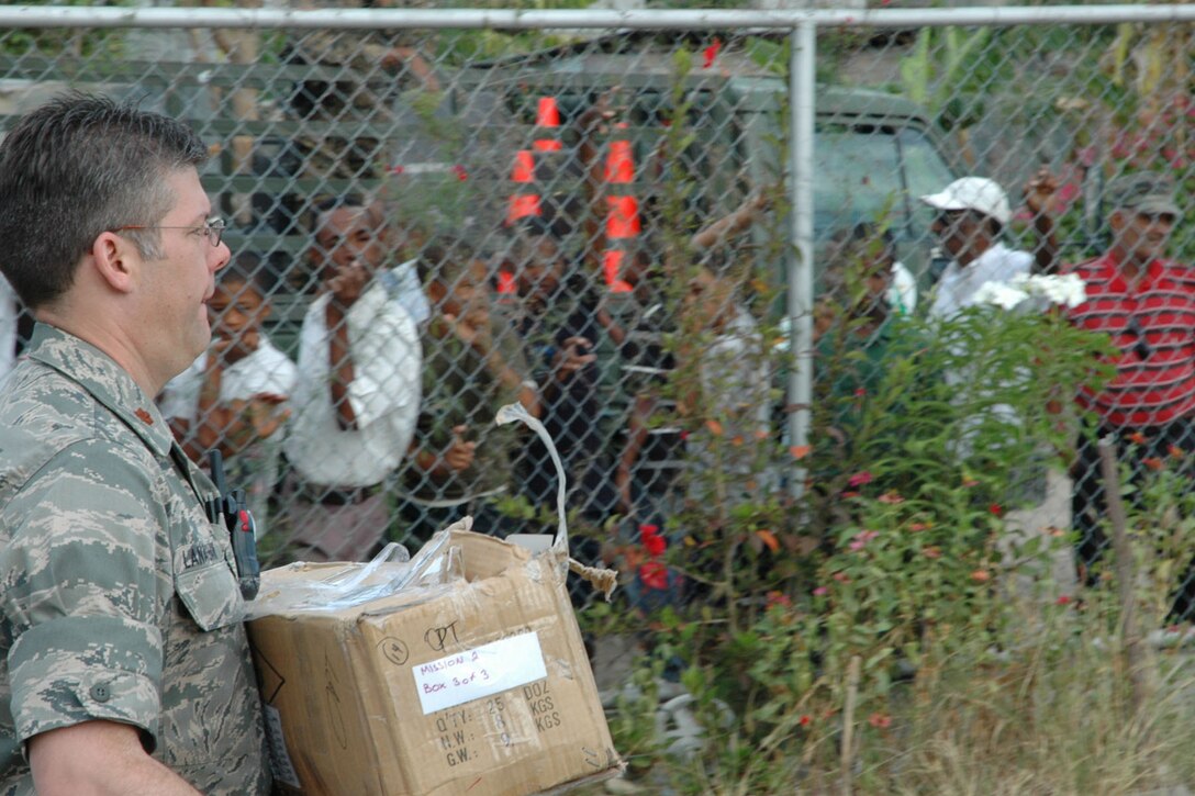 AZUA, Dominican Republic — U.S. Air Force Reserve Maj. Patrick Lanaghan, 910th Medical Squadron medical science officer, carries a box of medical supplies onto a school campus here. The school was one of three locations for Dominican Republic Medical Readiness Training Exercise (MEDRETE) 2009. Town residents standing outside the fence of the campus are among more than 10,000 Dominicans expected to receive much needed medical care during the mission that will also visit a site in the Dominican town of Padre Las Casas and another site in Azua. Maj. Lanaghan is among a team of more than 30 Citizen Airman who left from Youngstown Air Reserve Sation, Ohio, April 25 and are scheduled to return May 8. U.S. Air Force photo by Tech. Sgt. Dennis J. Kilker Jr.  