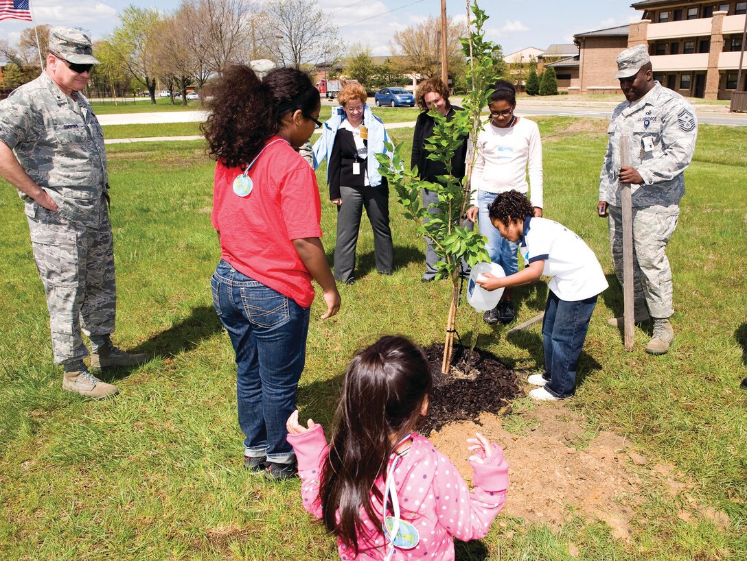 Brigadier Gen. Dana Simmons, Air Force Office of Special Investigations commander, left, looks on as Sidney Coker, 6, son of Senior Master Sgt. Kevin Coker, AFOSI first sergeant, right, pours water on a tree that AFOSI members and their children planted to beautify Andrews April 23. The children visited Andrews as AFOSI's part in National Take Our Daughters And Sons To Work Day. AFOSI believes that exposing children to what a parent does during the work day is important, and showing them the value of their education and helping them discover the power and possibilities associated with a balanced work and family life are keys to success. (U.S. Air Force photo/ Michael Hastings)