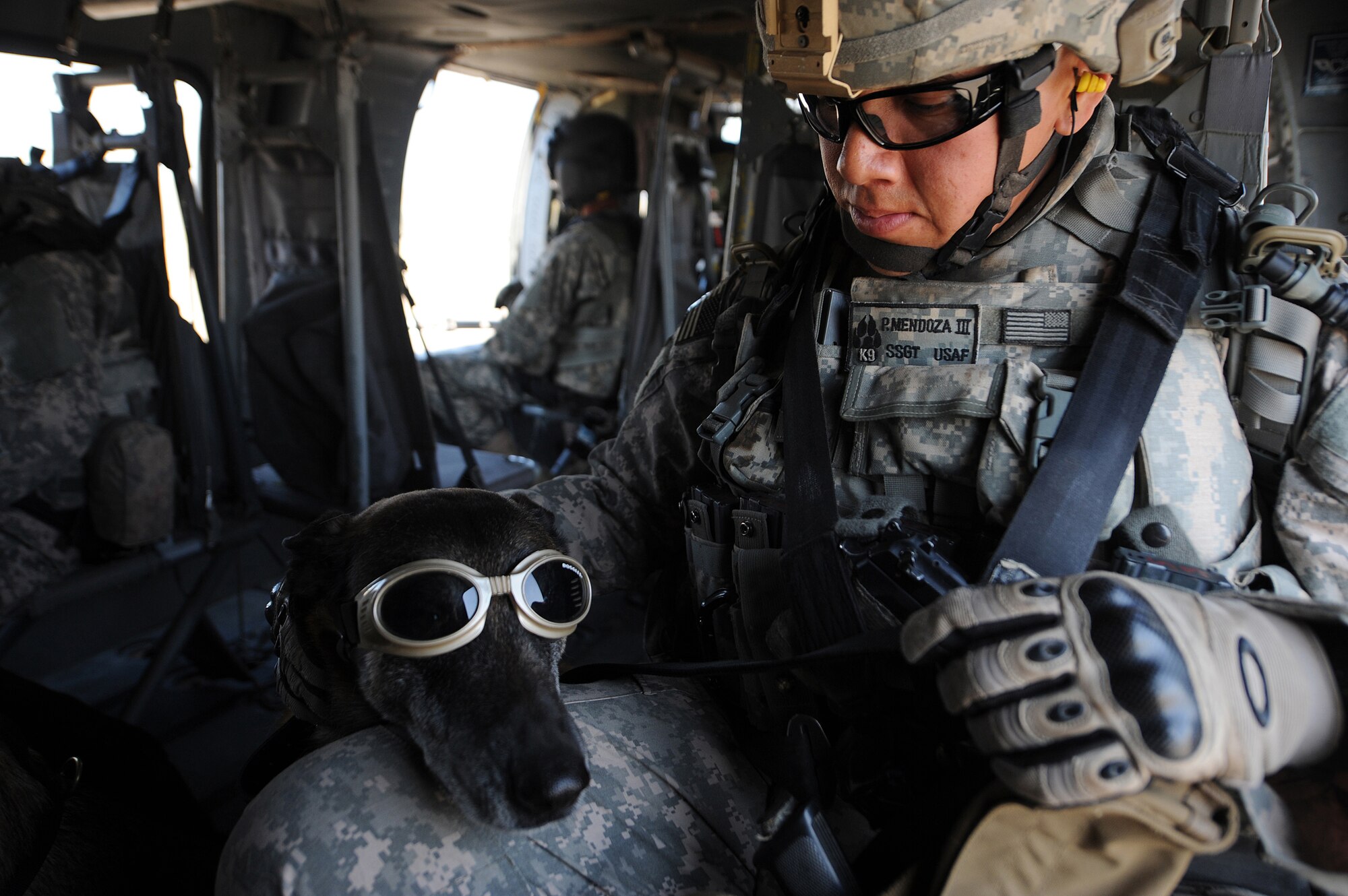 Staff Sgt. Philip Mendoza pets his military working dog, Rico, wearing "doggles," during training aboard a helicopter April 21 at Joint Base Balad, Iraq. The training teaches the team how to safely and properly enter and exit aircraft, and prepares the for future air-assault missions. Sergeant Mendoza is a 332nd Security Forces Group military working dog handler deployed from Moody Air Force Base, Ga. He is a native of Lancaster, Texas. (U.S. Air Force photo/Senior Airman Elizabeth Rissmiller) 
