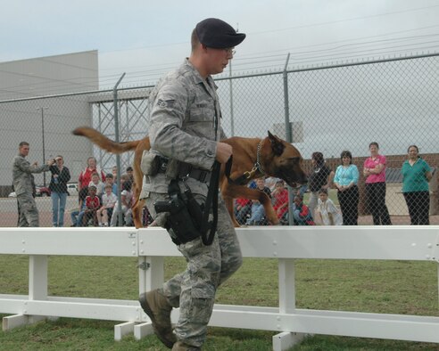 ALTUS AIR FORCE BASE, Okla. – Senior Airman Joshua Newbrey, 97th Security Forces Squadron, and Albert, military working dog (MWD), run the obstacle course as a demonstration for the ASPIRE, After School Program Intervention Remediation Enrichment, students of Altus.  Altus has 7 MWD that are dual certified in detection and patrol attack. (U.S. Air Force photo/Airman 1st Class Leandra D. Hernandez)