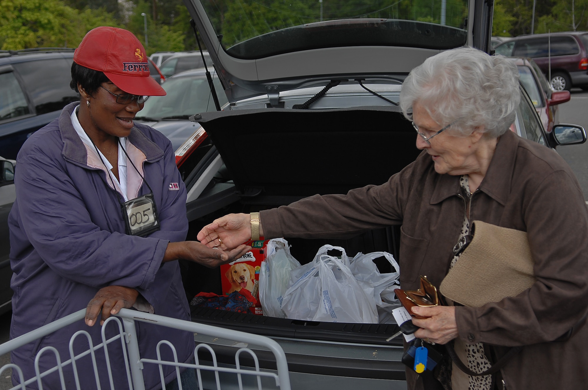Gaby Bogindi (left), commissary bagger, is tipped by a customer after bagging and loading her groceries in her car, Ramstein Air Base, Germany, April 23, 2009. Baggers are self-employed and work under a license agreement with the installation commander. (U.S. Air Force photo by Airman 1st Class Tony R. Ritter)

