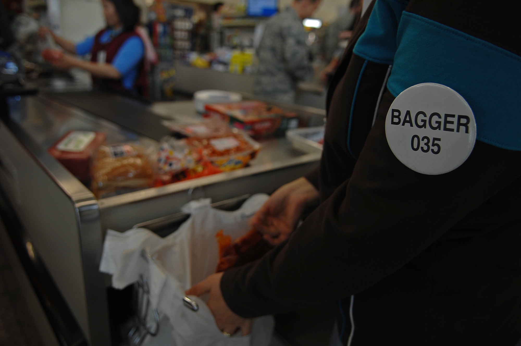 A commissary bagger bags a customer's  groceries, Ramstein Air Base, Germany, April 23, 2009. Baggers are self-employed and work under a license agreement with the installation commander. (U.S. Air Force photo by Airman 1st Class Tony R. Ritter)