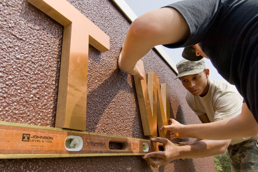 YOKOTA AIR BASE, Japan -- Senior Airmen Kurt Figueroa (foreground) and Steven McCain, 374th Civil Engineer Squadron structural shop apprentices, replace the 374th Airlift Wing lettering May 1 on the wing headquarters building. The wing was reorganized here April 1, 1992, and maintains the primary Western Pacific airlift hub for peacetime and contingency operations. (U.S. Air Force photo/Osakabe Yasuo)