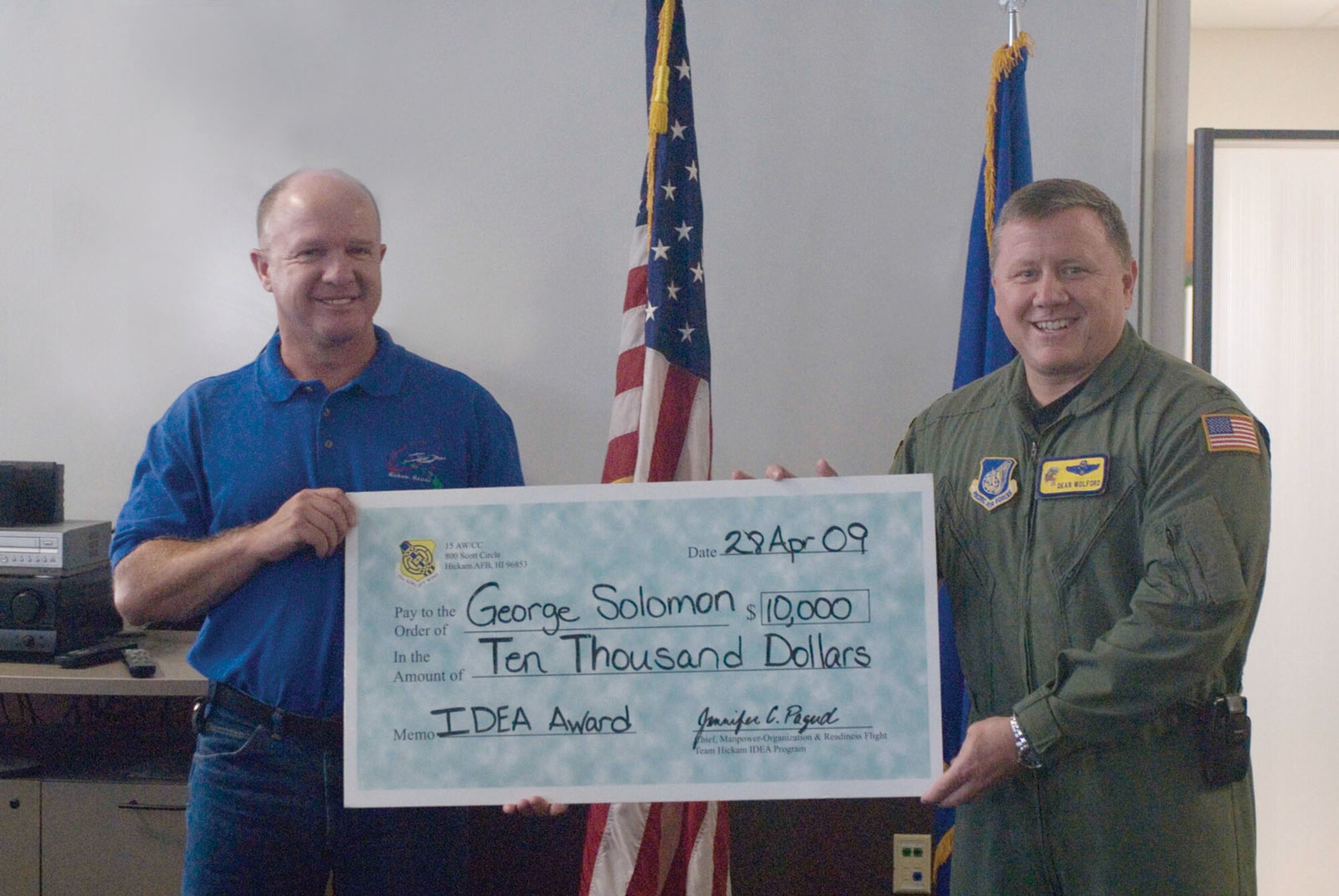 HICKAM AIR FORCE BASE, HAWAII – George Solomon receives a $10,000 check from 15th Airlift Wing vice commander Col. Dean Wolford at a commander’s call April 28 for a winning submission to the Innovative Development Through Employee Awareness (IDEA) Program. Mr. Solomon is a 15th Aircraft Maintenance squadron aircraft electrician who requested a source maintenance and recoverability code change that allowed a previously-expendable $16,631 C-17 ice detector to be repaired for about $5,000. In the last two years, 135 parts have been thrown away at a cost of $2,190,105; however, repairing the part would only have cost $769,500, which adds up to a total cost savings of $1,420,605 in two years. The IDEA Program is an incentive program that promotes process improvement and/or resource savings through ideas submitted by military and civilian employees. For more information, see Air Force Instruction 38-401 or call the 15th Mission Support Squadron Manpower-Organization and Readiness Flight at 448-IDEA. (U.S. Air Force photo illustration by Senior Airman Carolyn Viss)