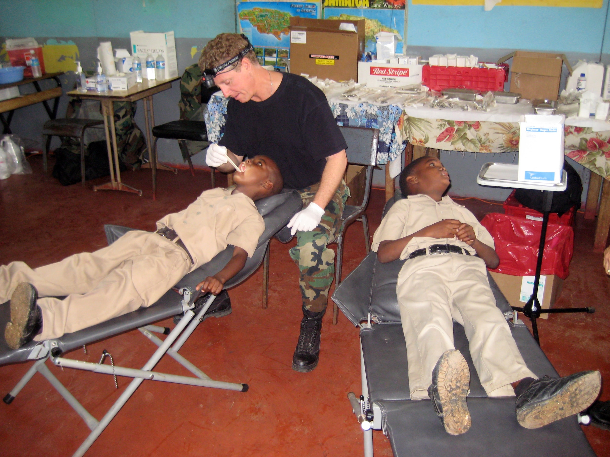 Lt. Col. (Dr.) Mark Emshwiller, an Arizona Air National Guard dentist, inspects the teeth of two Jamaican school children to identify cavities and offer referrals, if necessary. While at Lottery All Age School, Dr. Emshwiller saw 108 children in two hours. (Air National Guard photo by Maj. Christine Rhodes)