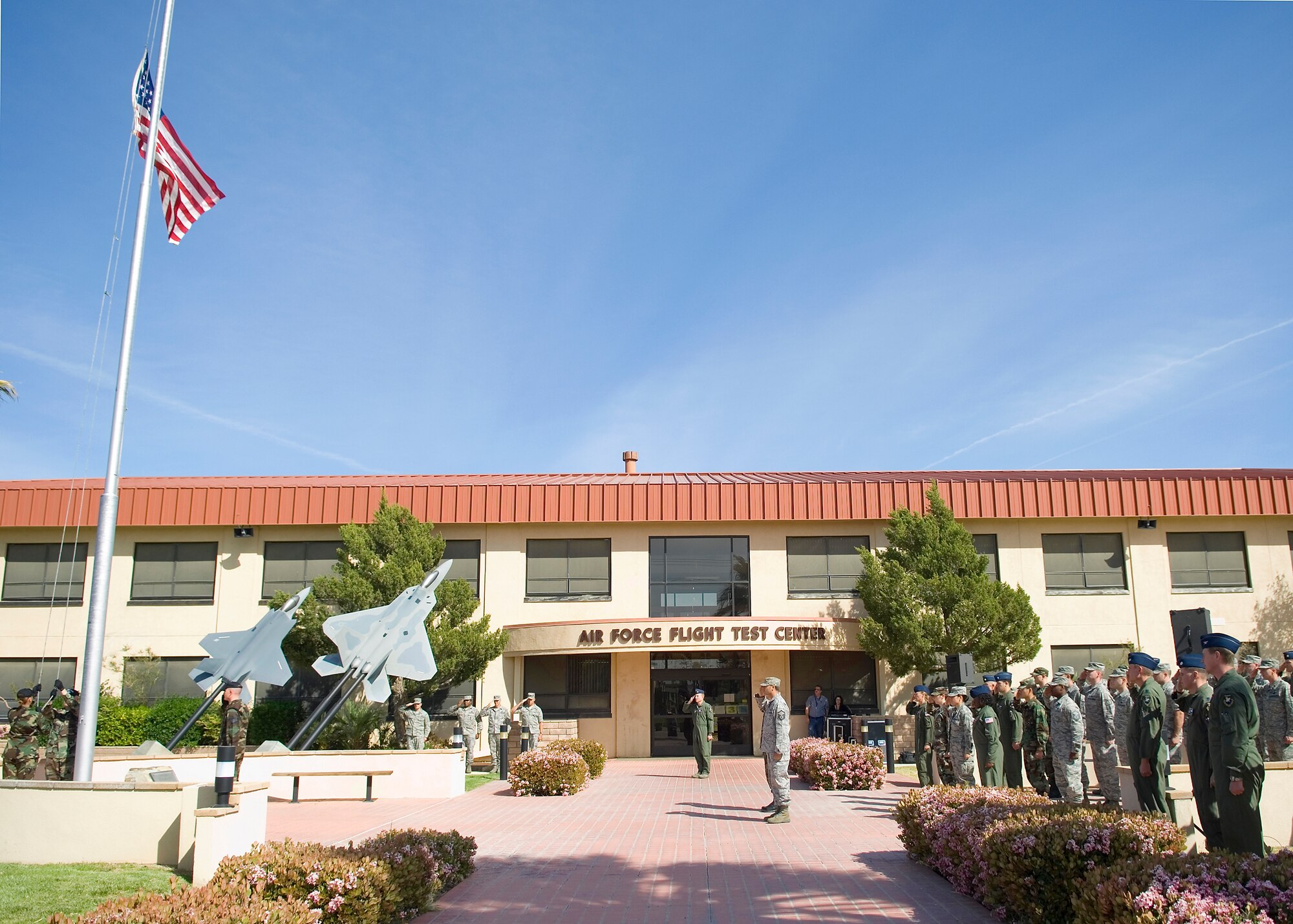 The Edwards Blue Eagle Honor Guard members lower the flag as Edwards Airmen salute during a retreat ceremony at the Air Force Flight Test Center Headquarters April 30. The 412th Operations Group hosted the retreat ceremony. (U.S. Air Force photo/Mike Cassidy)