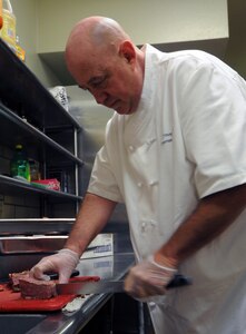 Michael Young, a certified executive chef, cuts meat in preparation for a meal at the Parr O?Club May 1. Mr. Young is leading the kitchen crew at both the officers club and the Kendrick Club in a new direction, adding a new spark of flare to the menu at the clubs. (U.S. Air Force photo by Steve White)