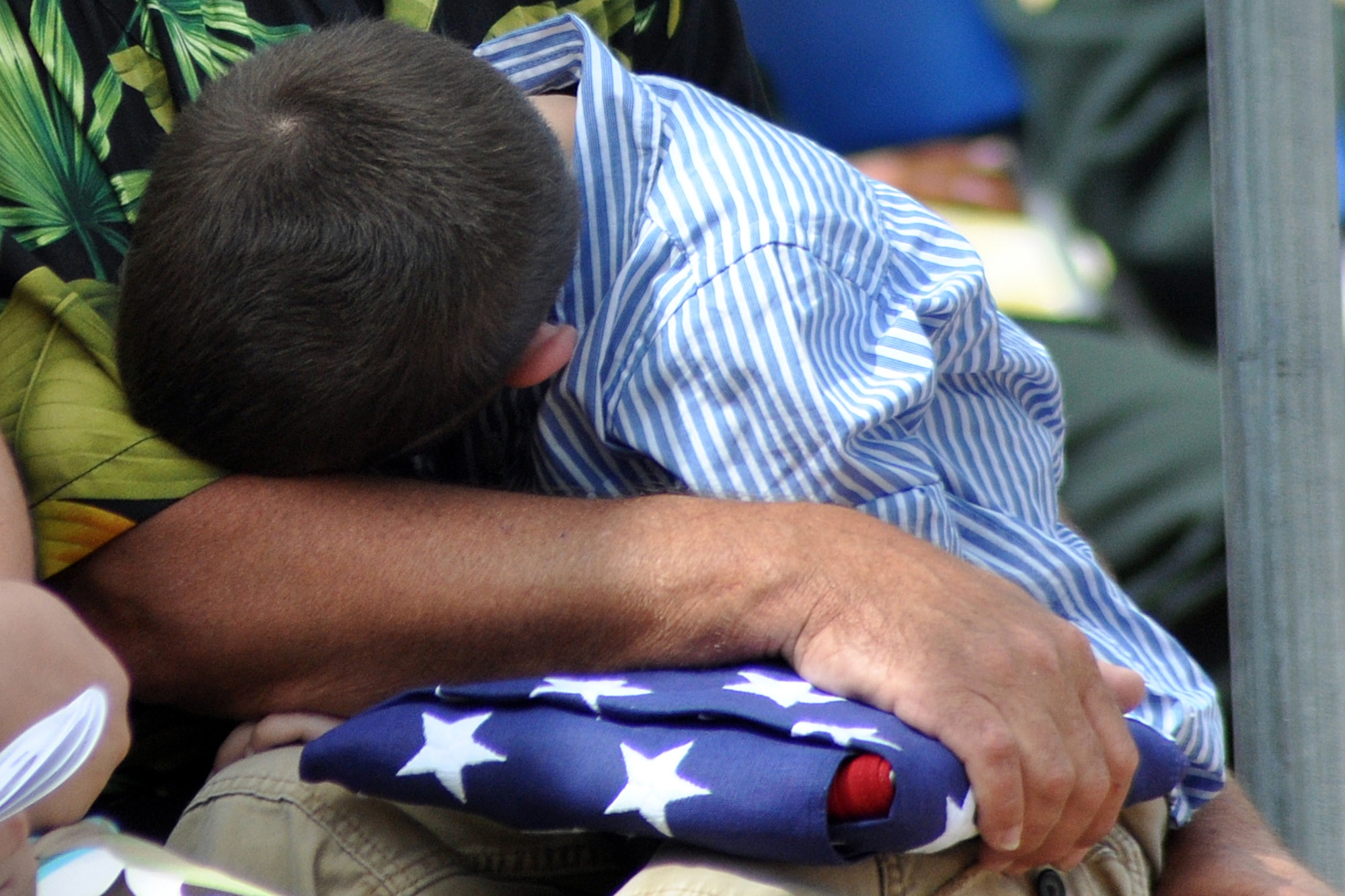 EGLIN AIR FORCE BASE, Fla. -- Michael buries his head in his grandfather, Larry's lap after his family received an American flag in honor of Marine Staff Sgt. Christopher Strickland, an EOD technician who died in the line of duty June 25, 2008 in Afghanistan. The ceremony was part of the 40th Annual Explosive Ordnance Disposal Memorial Service May 2, held at the Kauffman EOD Training Complex. Six servicemembers were added to the memorial wall bringing the total to 238 names. The men and women whose names are on the Memorial must be graduates of an approved EOD School who have given their lives on active duty as a result of an EOD mission since the declaration of World War II. (U.S. Air Force photo/ Airman Anthony Jennings)