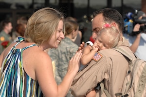 U.S. Air Force Tech. Sgt. Augie Nalsen reunites with wife, Christina, and daughter, Cali, at Charleston Air Force Base, S.C., May 3, 2009.  More than 140 Airmen from the 16th Airlift Squadron returned from their 120-day deployment to the Middle East supporting Operations Enduring and Iraqi freedom and operations in the Horn of Africa. While deployed, the 16 AS executed 142 airdrops, more than any of its predecessors, which resupplied service members serving in the regions with 3.7 million pounds of supplies. Sergeant Nalsen is a loadmaster for the 16 AS. (U.S. Air Force photo by James M. Bowman)(Released)