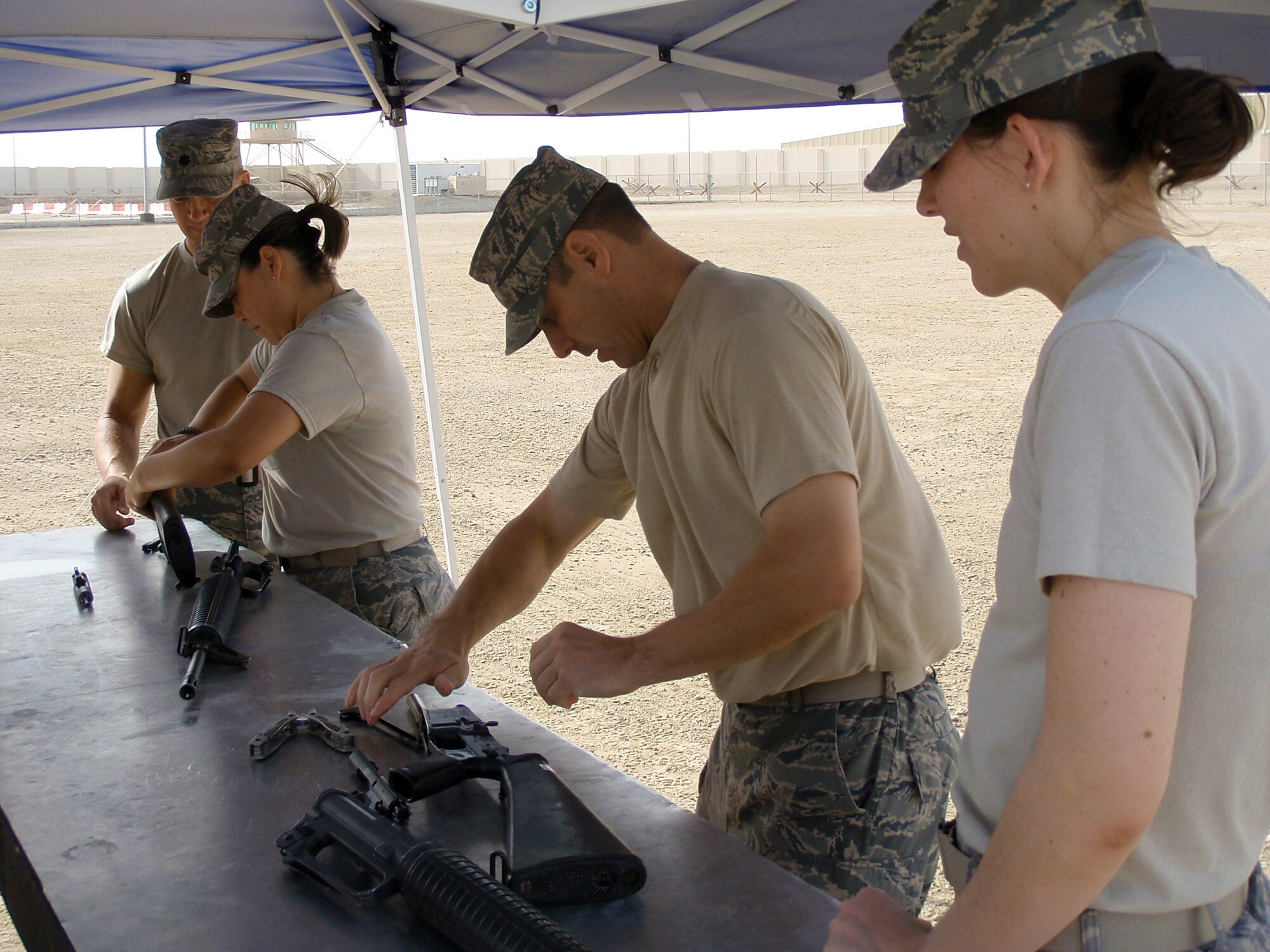 Staff Sgt. Christian Johnson and Master Sgt. James Gantar take an M-16 rifle apart as teammates Lt. Col. Fredrick Thaden and 1st Lt. Miranda Thompson look on during on a Defender Challenge event April 25 at an air base in Southwest Asia. Each team had to dismantle and put back together an M-16 as fast as they could. Sergeant Gantar is deployed from Grand Forks Air Force Base, N.D., and hails from Girard, Ohio. Sergeant Johnson is deployed from Tyndall AFB, Fla., and hails from Brownsville, Texas. Lieutenant Thompson is deployed from Malmstrom AFB, Mont., and hails from Fleshing, Ohio. Colonel Thaden is a permanent party member at the 380th Air Expeditionary Wing and hails from Utah. All are assigned to the 380th Expeditionary Mission Support Group. (Courtesy photo)
