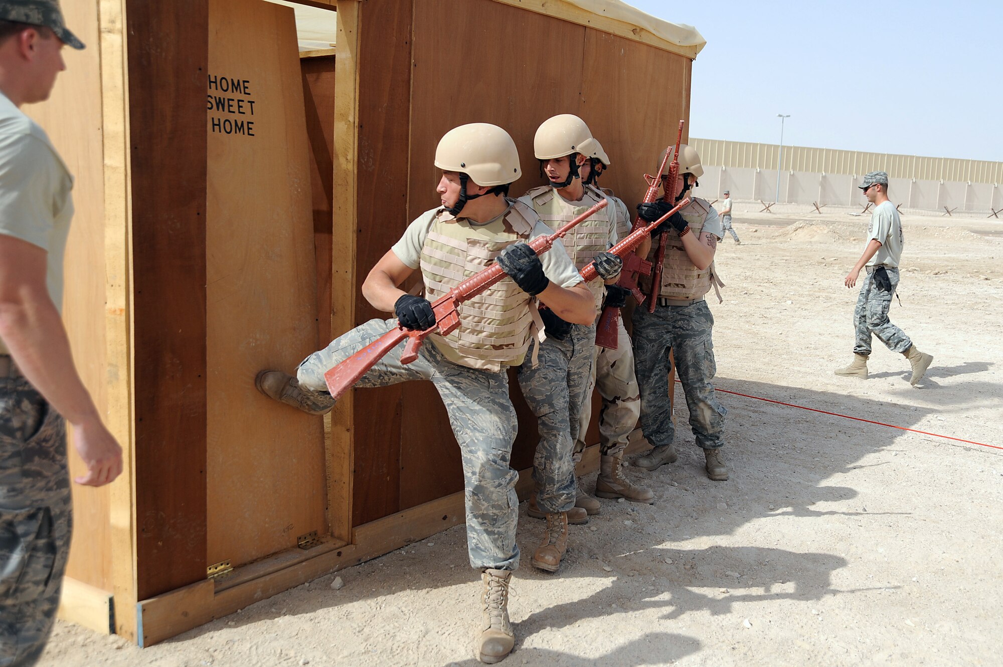 Senior Airman Matthew McCarthy kicks down a door on a tactical entry trainer as Staff Sgt. Cory Bobo, Senior Airman Paulo Giraldo and Senior Airman Erin Kinney wait to enter during a Defender Challenge course April 25 at an air base in Southwest Asia. At the end of the course, the team would have to identify everything they saw inside to earn points toward their score. Airman McCarthy, Sergeant Bobo and Airman Giraldo are with the 380th Expeditionary Civil Engineer Squadron and Airman Kinney is with the 380th Expeditionary Security Forces Squadron. The team won the competition beating out the second place team by one second. Airman McCarthy is deployed from Bolling Air Force Base, D.C., and hails from Omaha, Neb. Sergeant Bobo is deployed from Aviano Air Base, Italy and hails from Athens, Ohio. Airman Giraldo is deployed from Bolling AFB and hails from Revere, Mass. Airman Kinney is deployed from Tinker AFB, Okla., and hails from Austin, Texas. (U.S. Air Force photo/Senior Airman Brian J. Ellis) 
