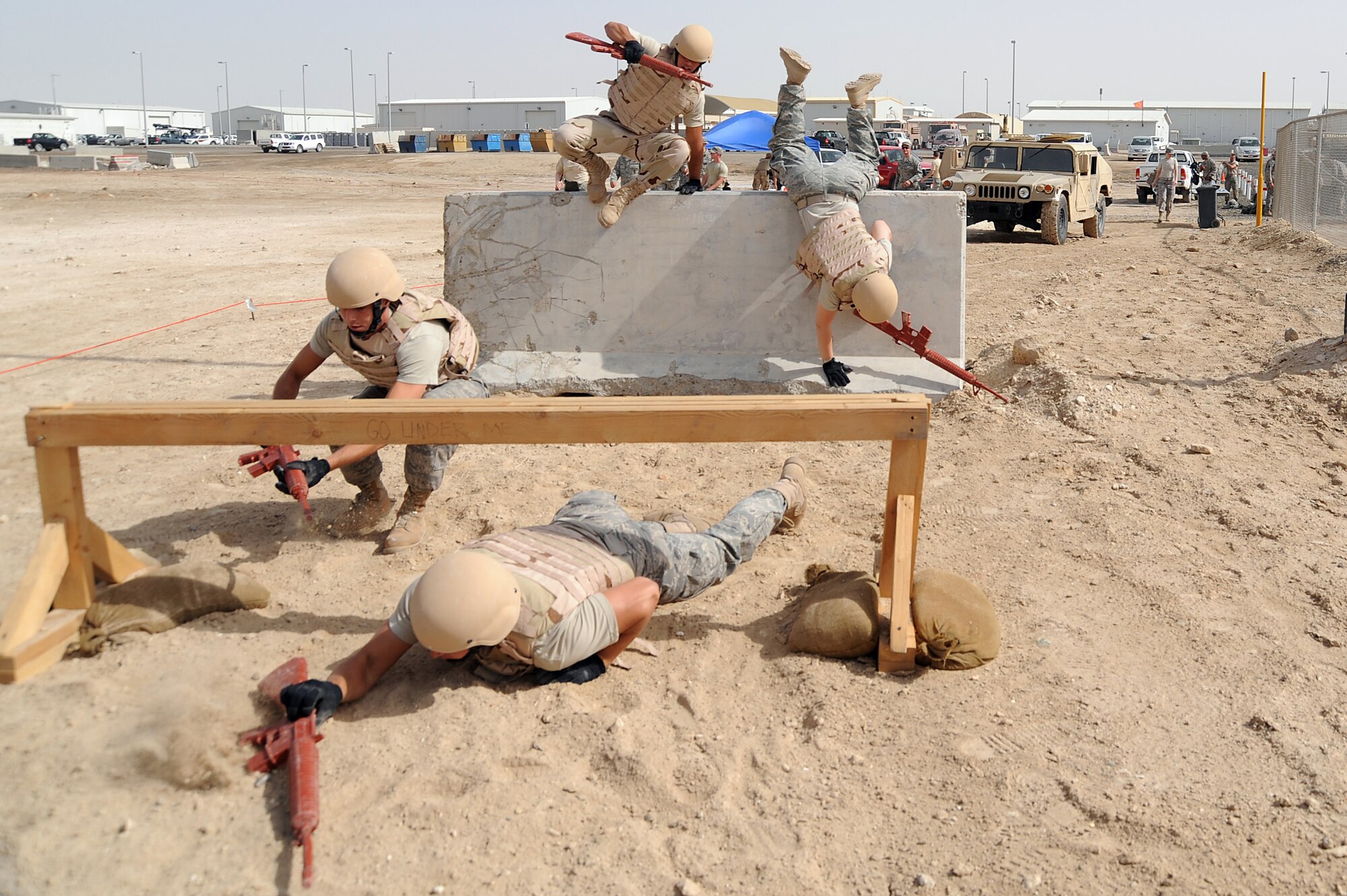 Senior Airman Matthew McCarthy low crawls under a wood barrier as Staff Sgt. Cory Bobo follows while Senior Airman Paulo Giraldo and Senior Airman Erin Kinney jump a 4 foot jersey barrier on a Defender Challenge course April 25 at an air base in Southwest Asia. Airman McCarthy, Sergeant Bobo and Airman Giraldo are with the 380th Expeditionary Civil Engineer Squadron and Airman Kinney is with the 380th Expeditionary Security Forces Squadron. The team won the competition beating out the second place team by one second. Airman McCarthy is deployed from Bolling Air Force Base, D.C., and hails from Omaha, Neb. Sergeant Bobo is deployed from Aviano Air Base, Italy and hails from Athens, Ohio. Airman Giraldo is deployed from Bolling AFB and hails from Revere, Mass. Airman Kinney is deployed from Tinker AFB, Okla., and hails from Austin, Texas. (U.S. Air Force photo/Senior Airman Brian J. Ellis) 