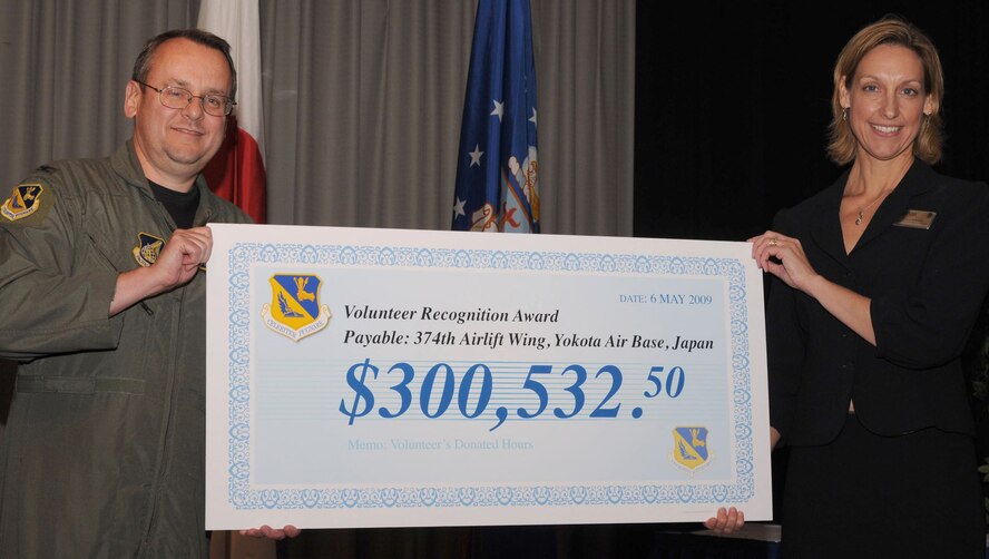 YOKOTA AIR BASE, Japan -- Kristine Galbreath, Yokota Airman and Family Readiness Center director, presents Col. Frank Eppich, 374th Airlift Wing vice commander, with a check May 6 at the base's Annual Volunteer Recognition Ceremony. The dollar amount represents the monetary equivalent of the 16,650 volunteer hours donated by base residents in 2008. (U.S. Air Force photo/Airman 1st Class Devin Doskey)